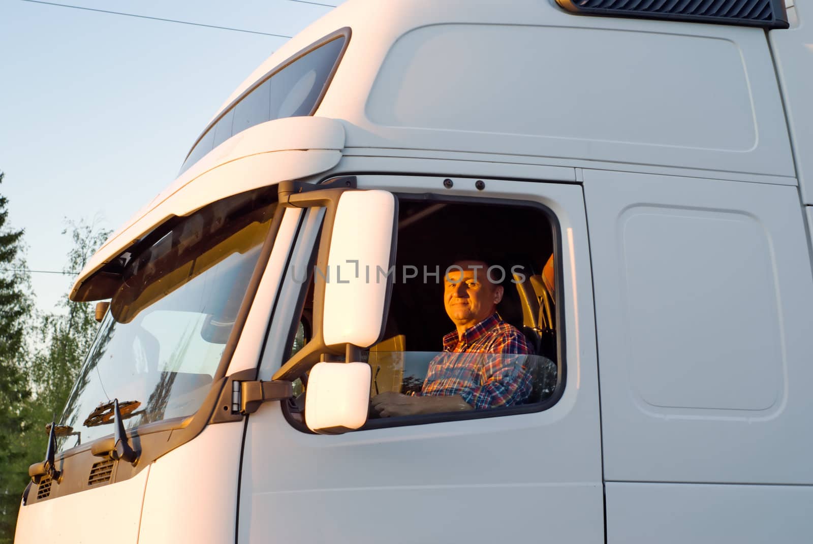 The driver in a cabin of the truck in the evening