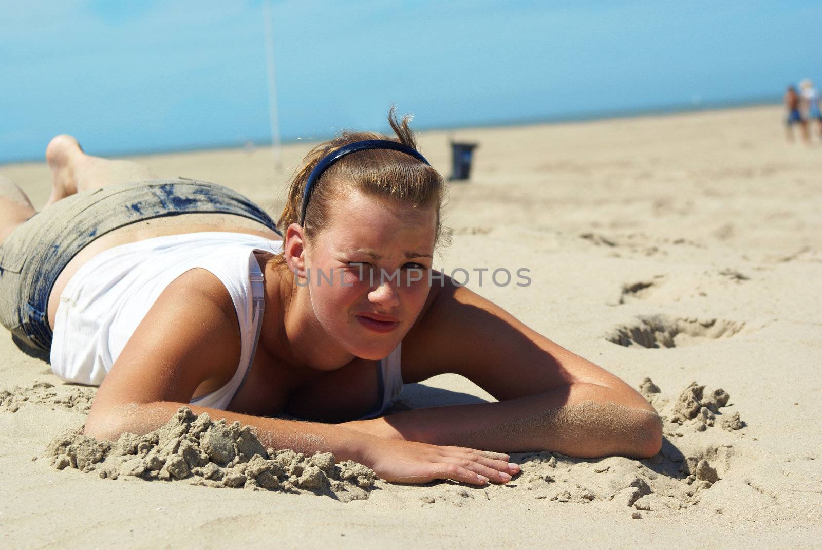 Pretty teen girl laying on a sandy beach.          