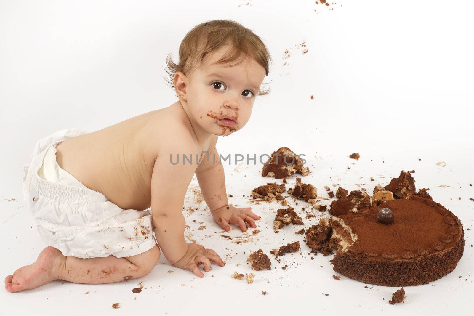 An adorable one year old girl enjoying her first birthday cake.
