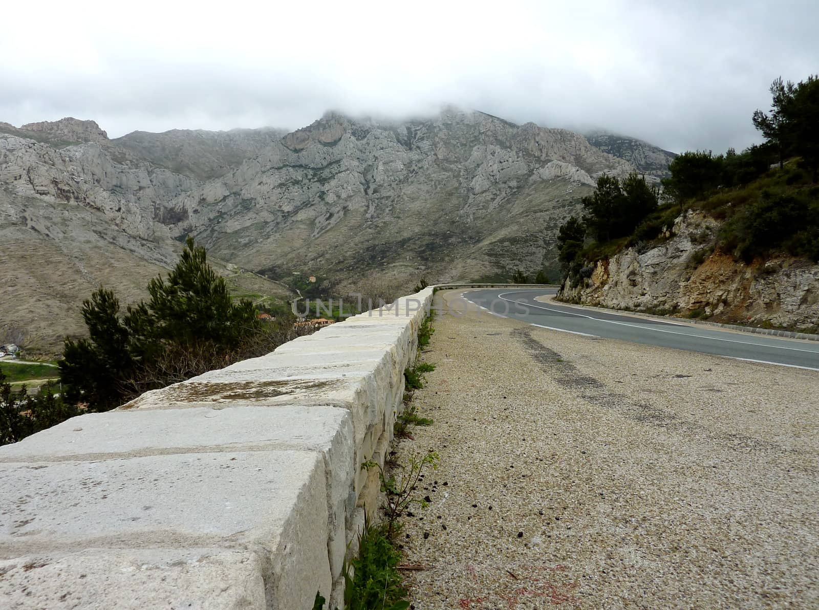 Road and white wall in a rocky mountain by cloudy weather