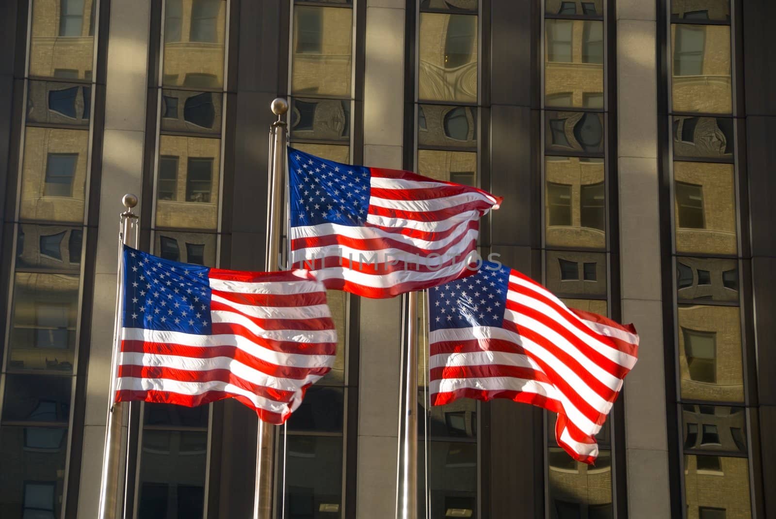 3 american flags against building