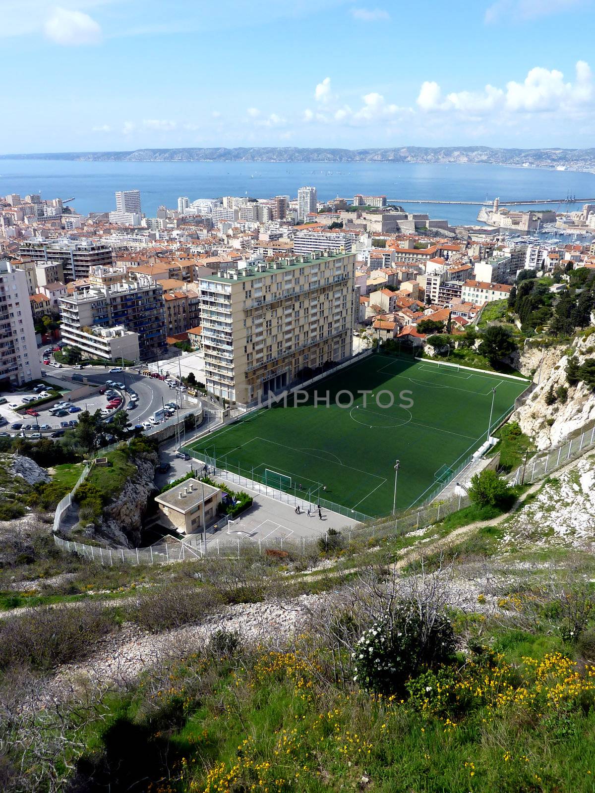 View of Marseilles city, France, with its buildings, the mediterranean sea and a football pitch by beautiful weather