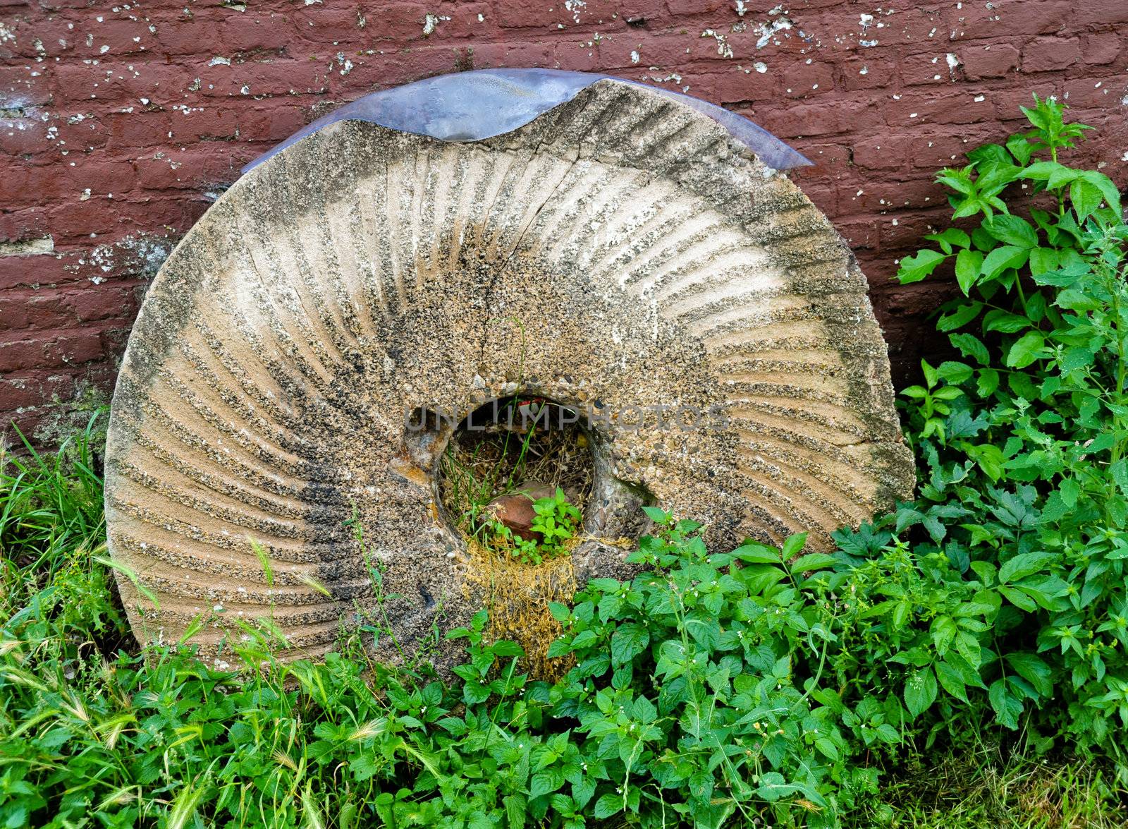 Old broken mill stone at the foot of a closed windmill