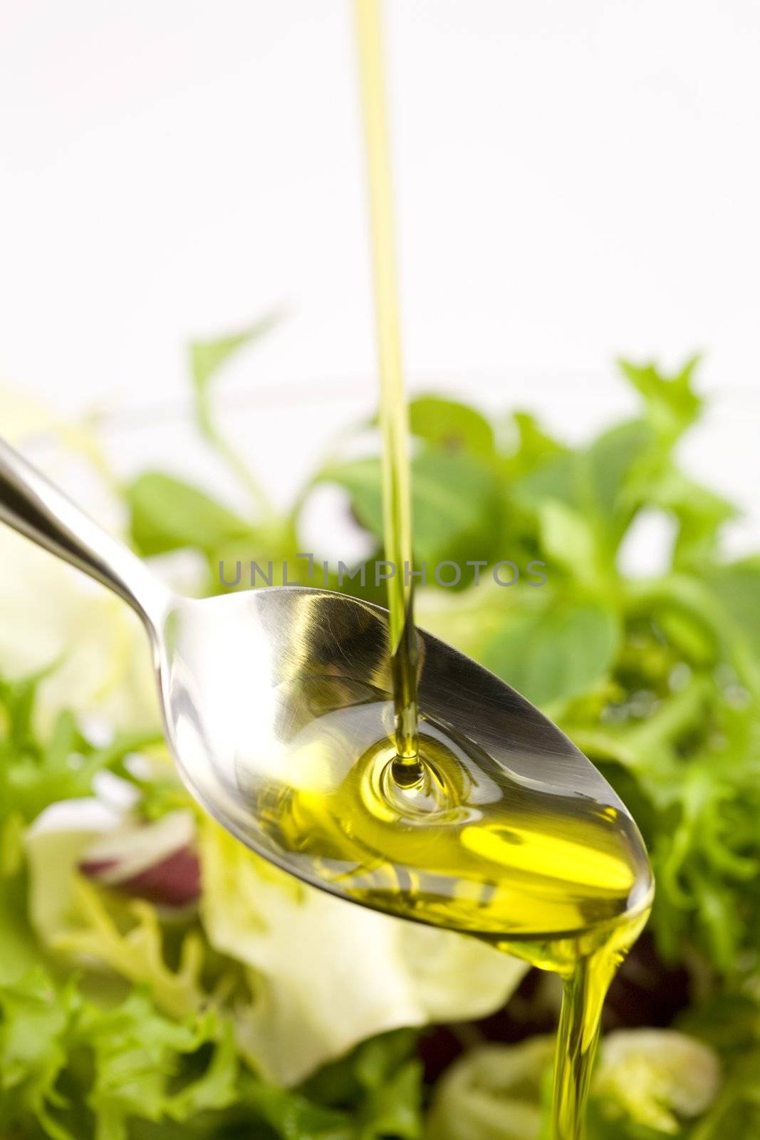 Pouring olive oil in the salad over a spoon