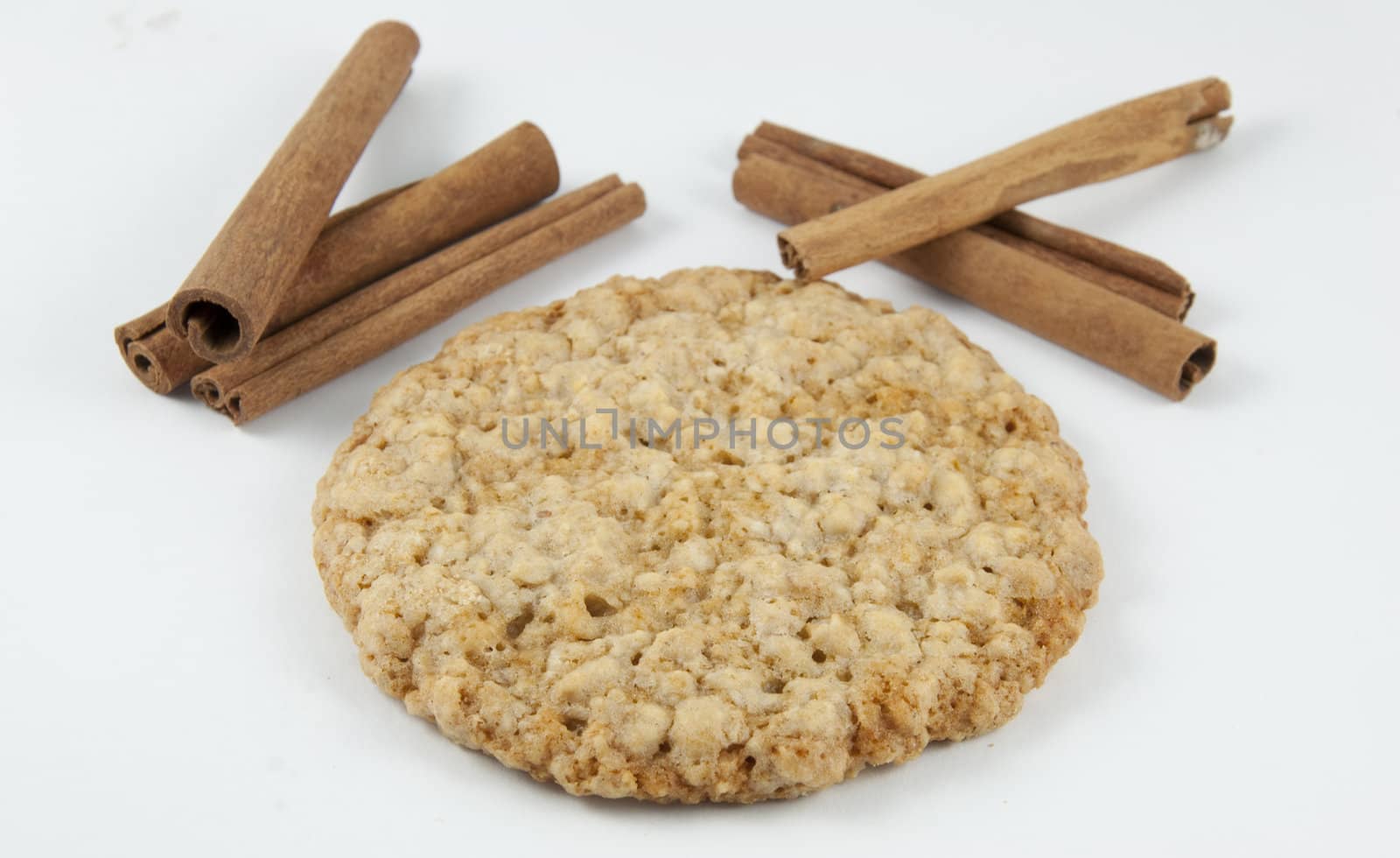 A oatmeal cookie next to cinnamon.
