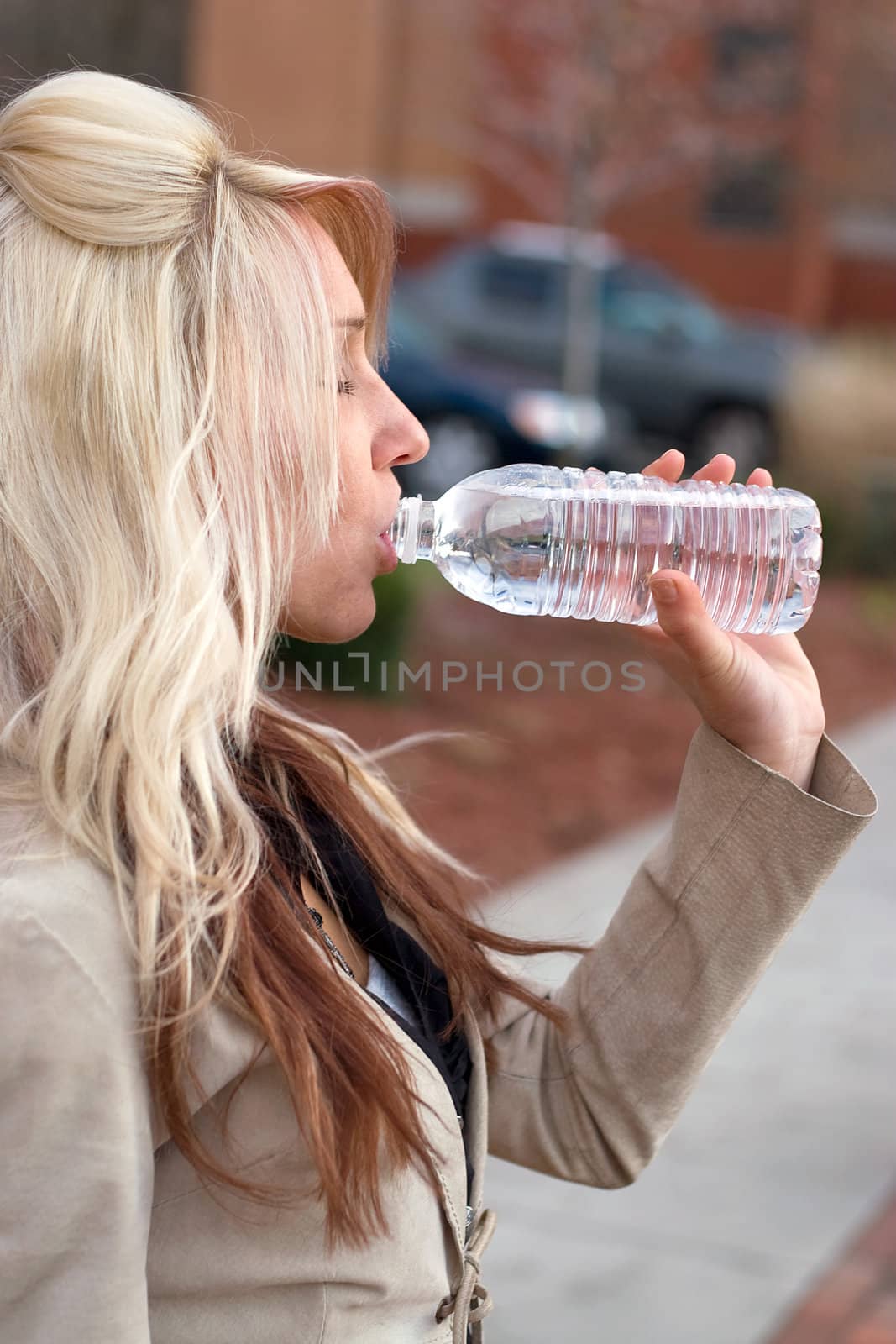 This young blonde female is drinking some bottled water.