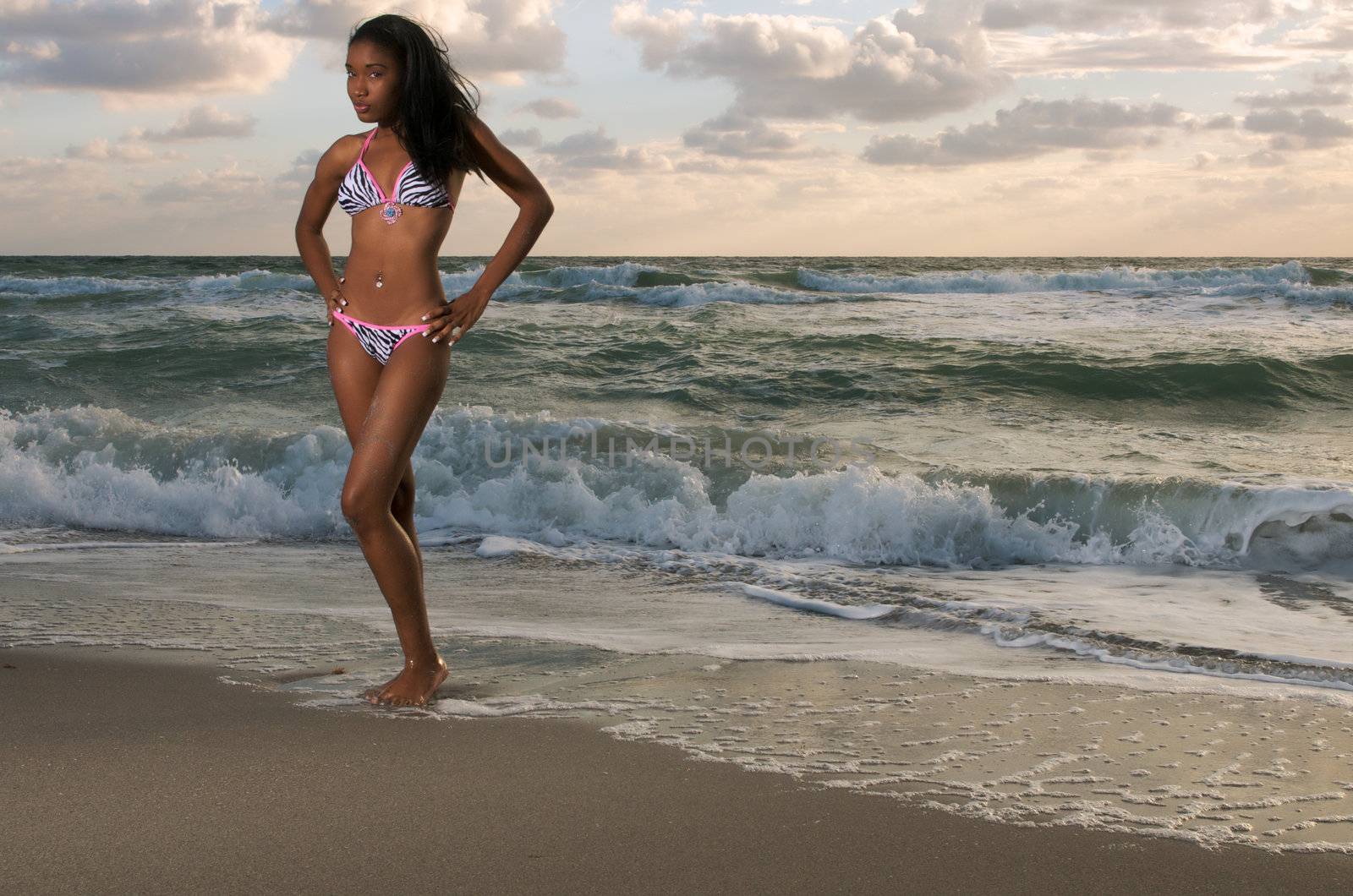 Young african american girl stands in the beach at sunrise.