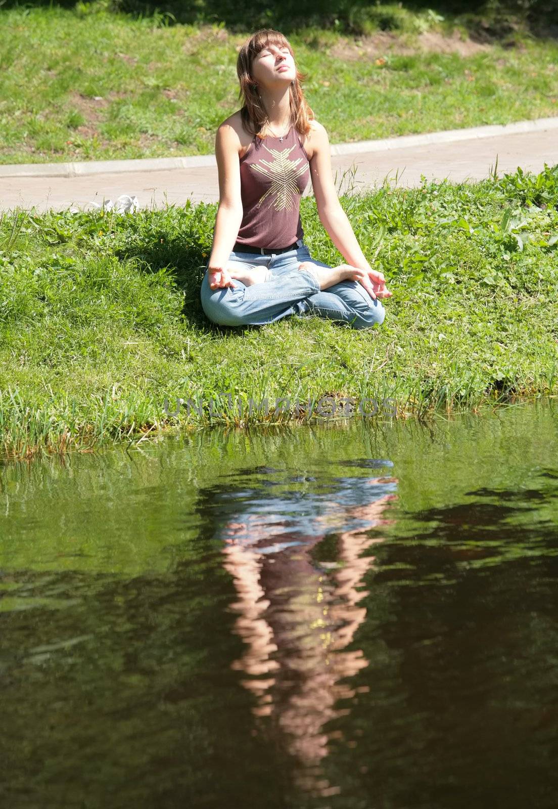beautiful girl is meditating near by water with reflections