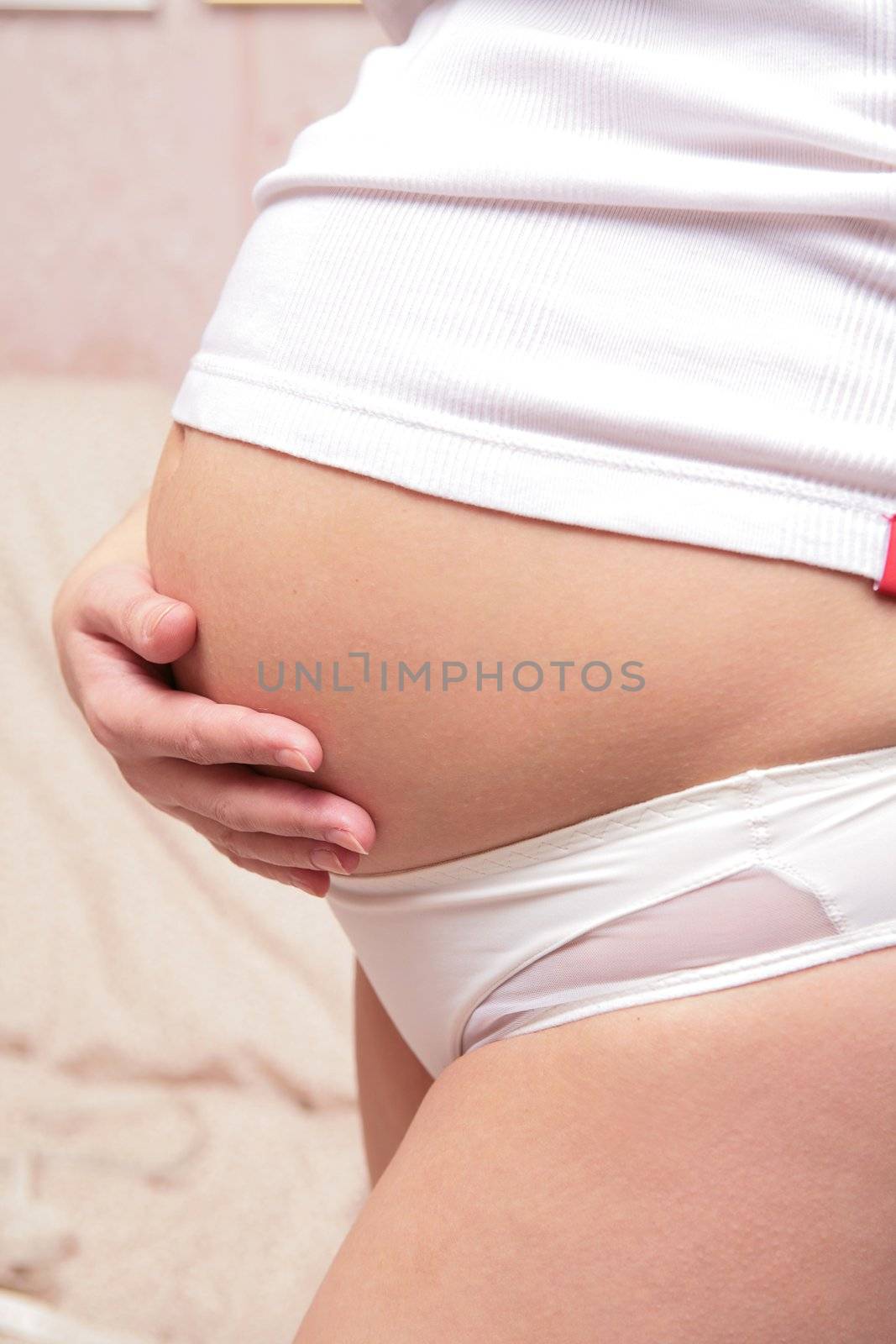 beautiful and graceful Expectant mother in white underwear is stroking belly