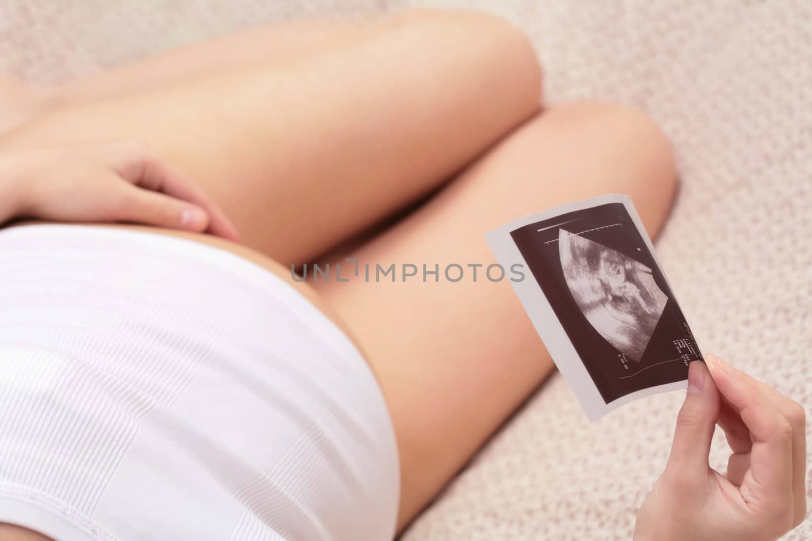 expectant mother looks at ultrasonic portrait its child
