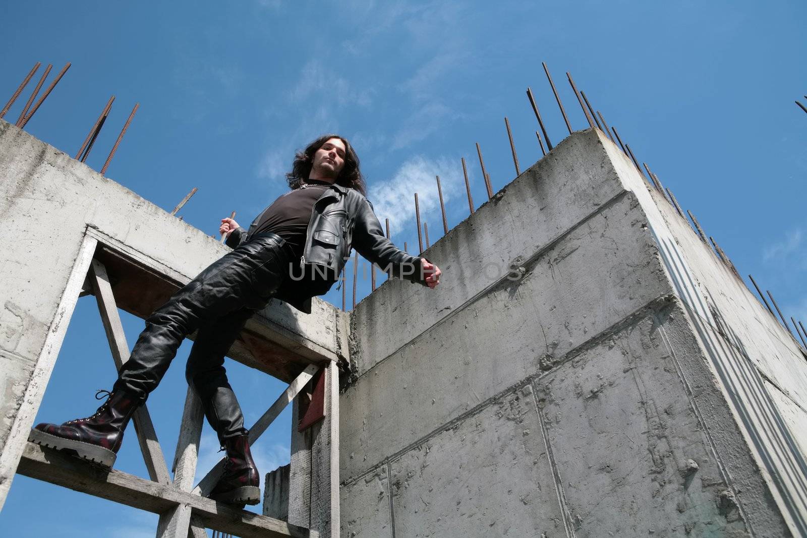 man in black leather cloth amongst iron-concrete construction