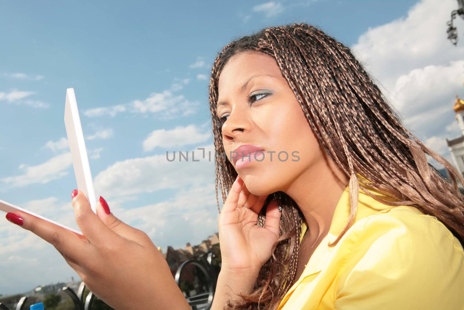 girl in yellow cloth looks at oneself in mirror and corrects make-up, close-up portrait