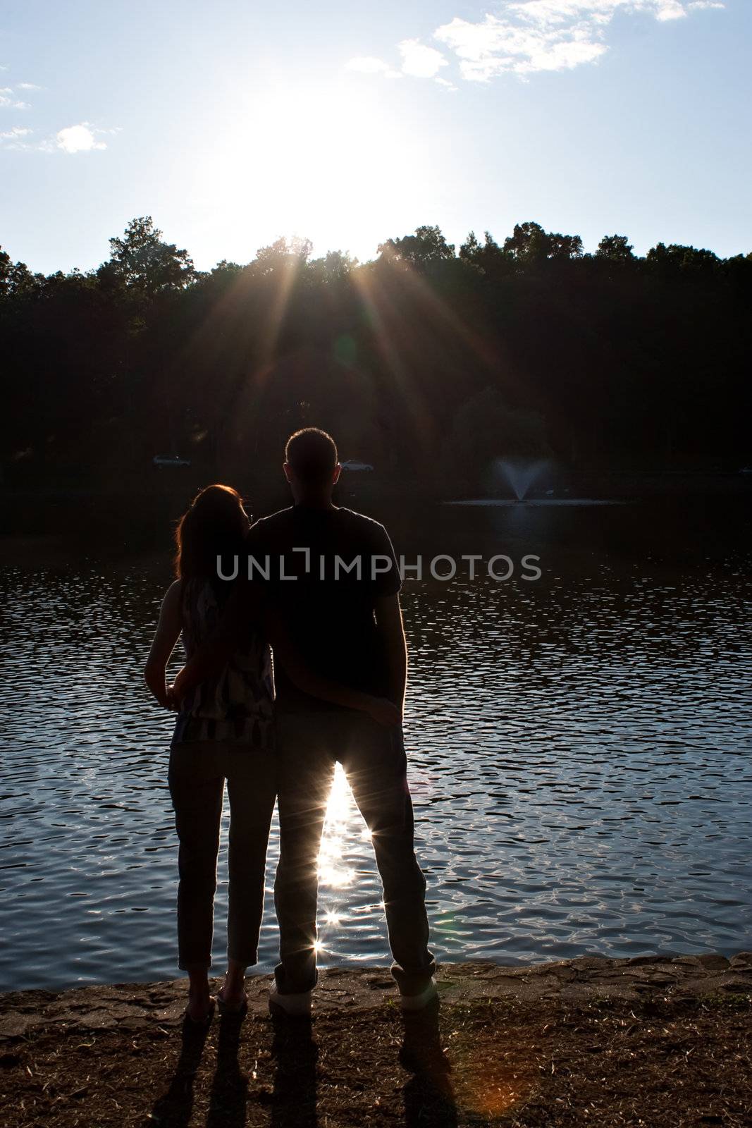 Silhouette of an affectionate couple embracing each other in the early evening hours with back lit lighting.