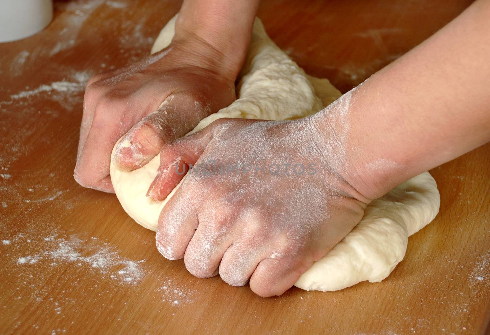 woman hands knead dough on wooden table