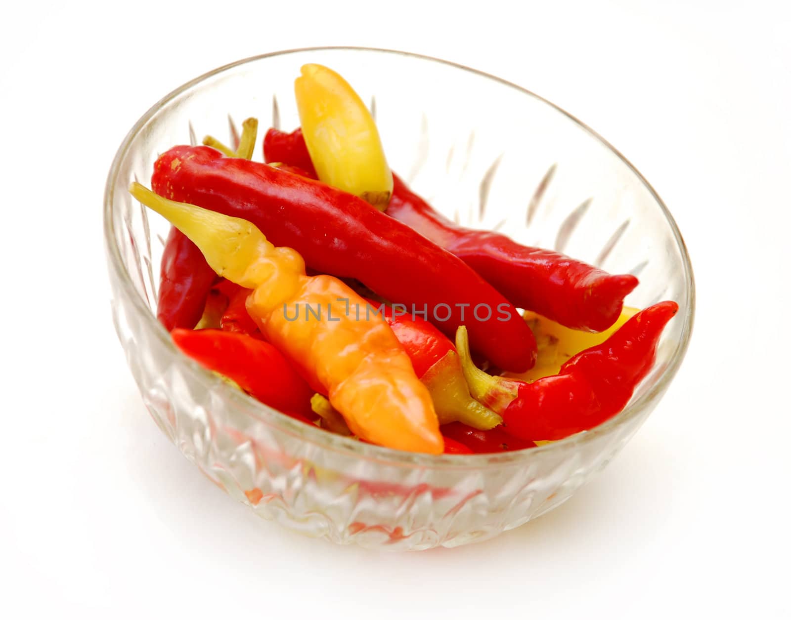 red and yellow hot peppers in glass bowl isolated over white