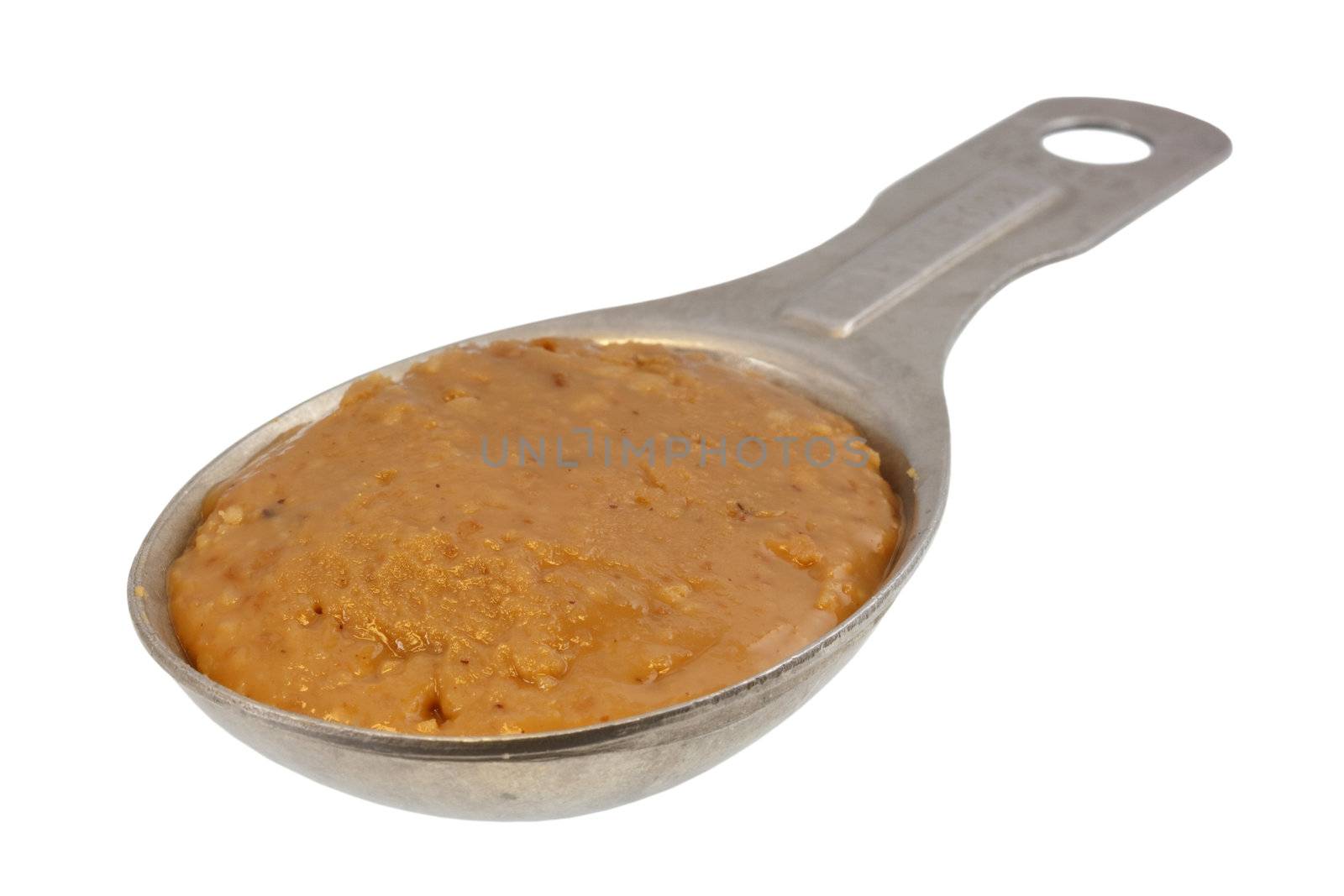 creamy peanut butter on aluminum measuring tablespoon isolated with clipping path