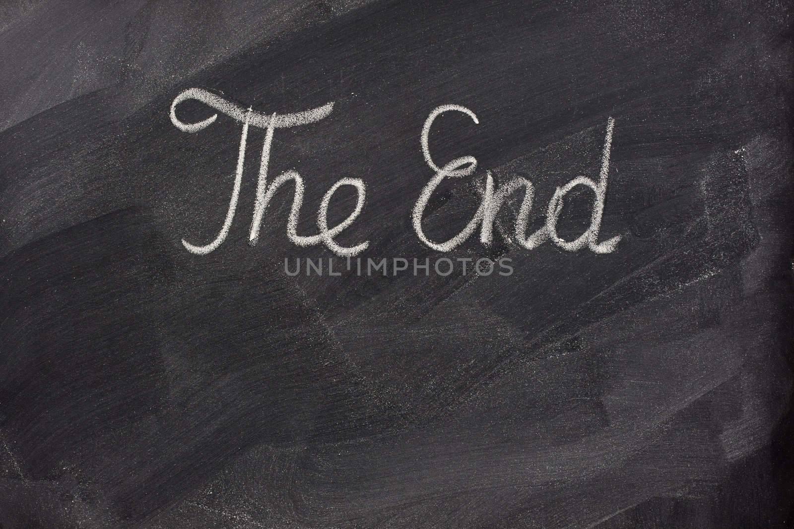 The end - handwritten with white chalk on blackboard with eraser smudges