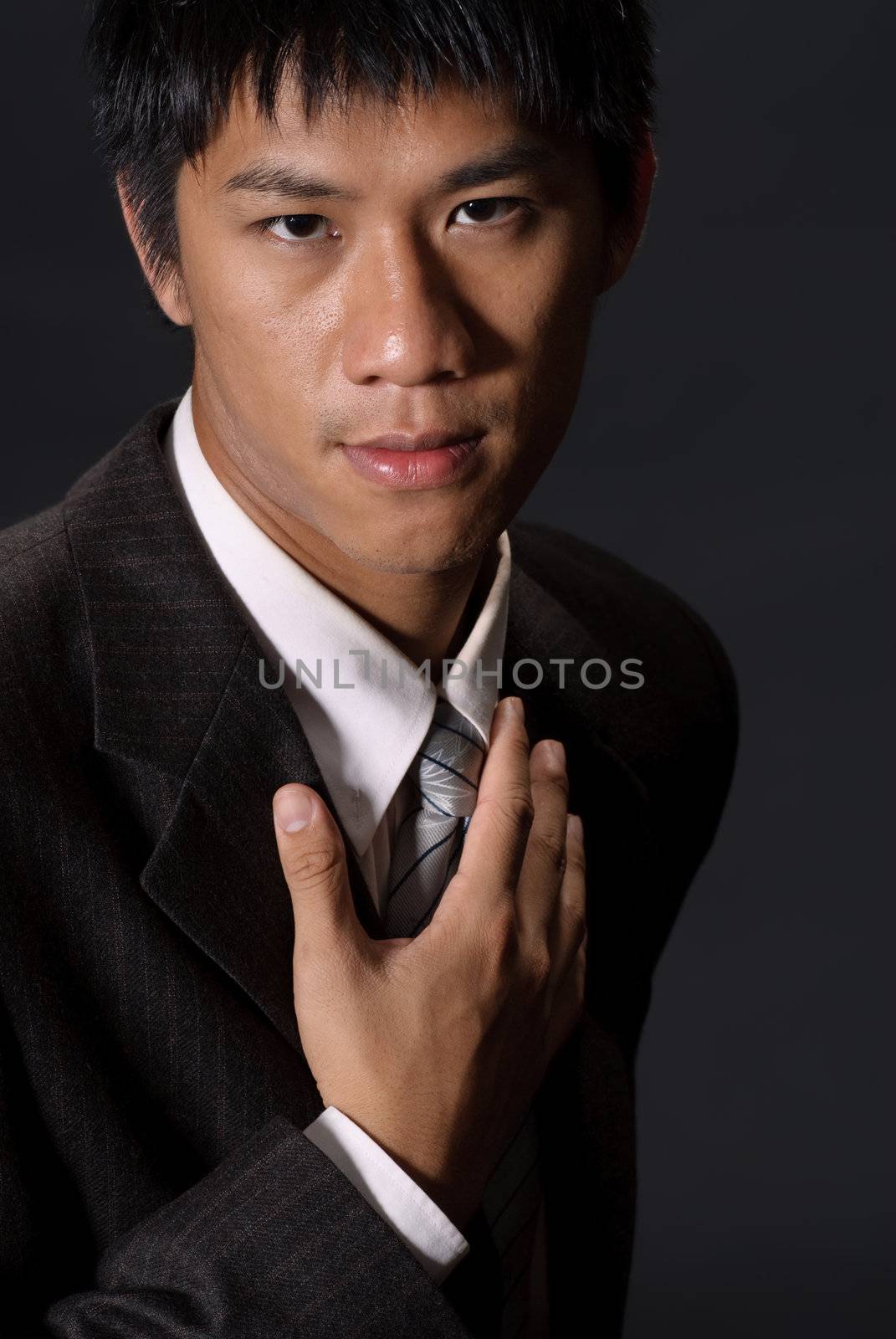 Young businessman of Asian, closeup portrait of handsome guy in studio in dark.