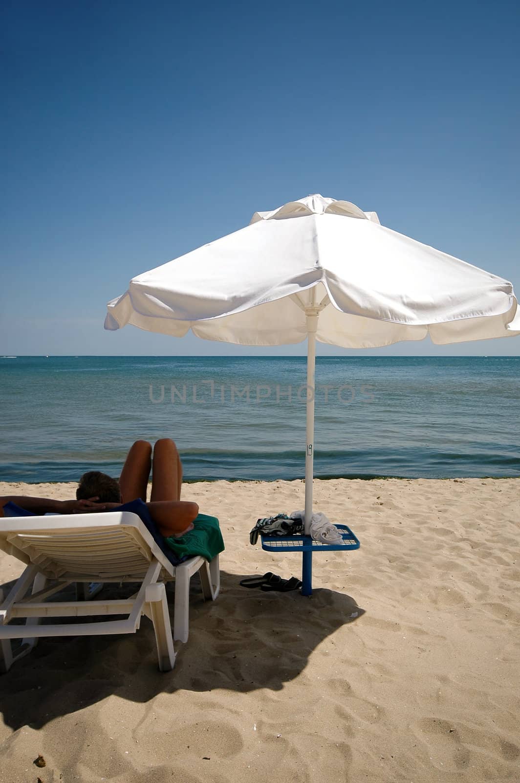 Man, umbrella and sunbed. Taken on a sunny day.