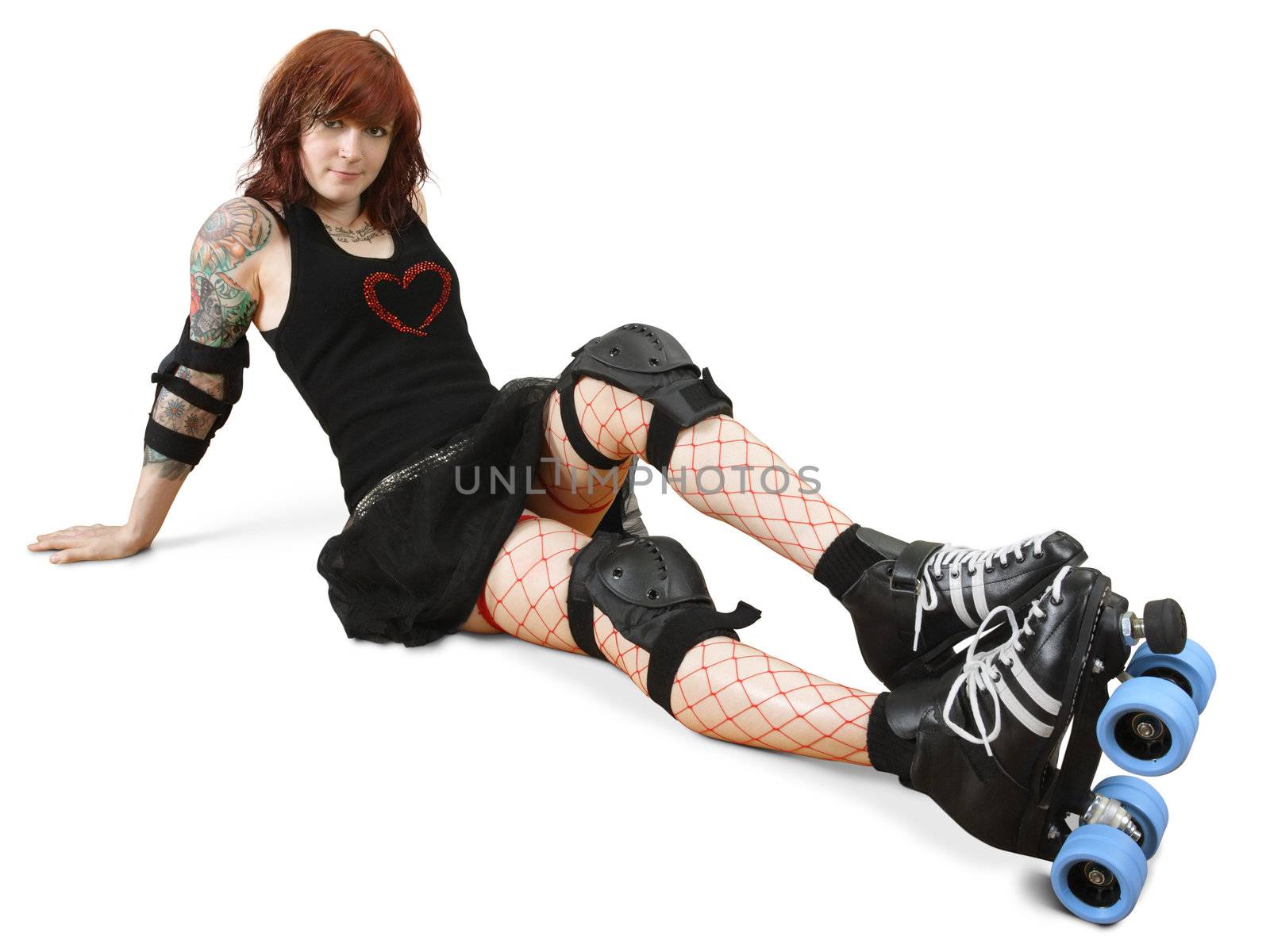 Photograph of a roller derby girl posing on the floor with her equipment.