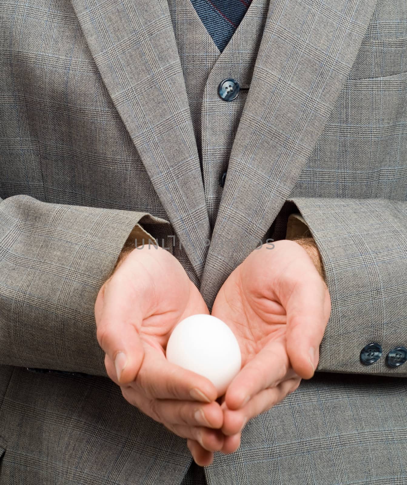 Closeup of a white egg in the hands of a businessman, symbolizing new hope or a new beginning