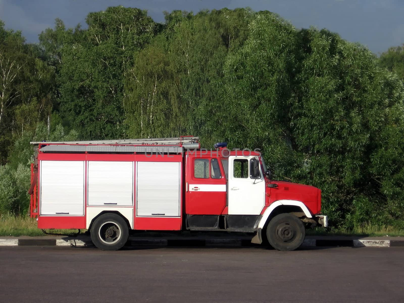 Red Russian fire truck at the road on a background of tree