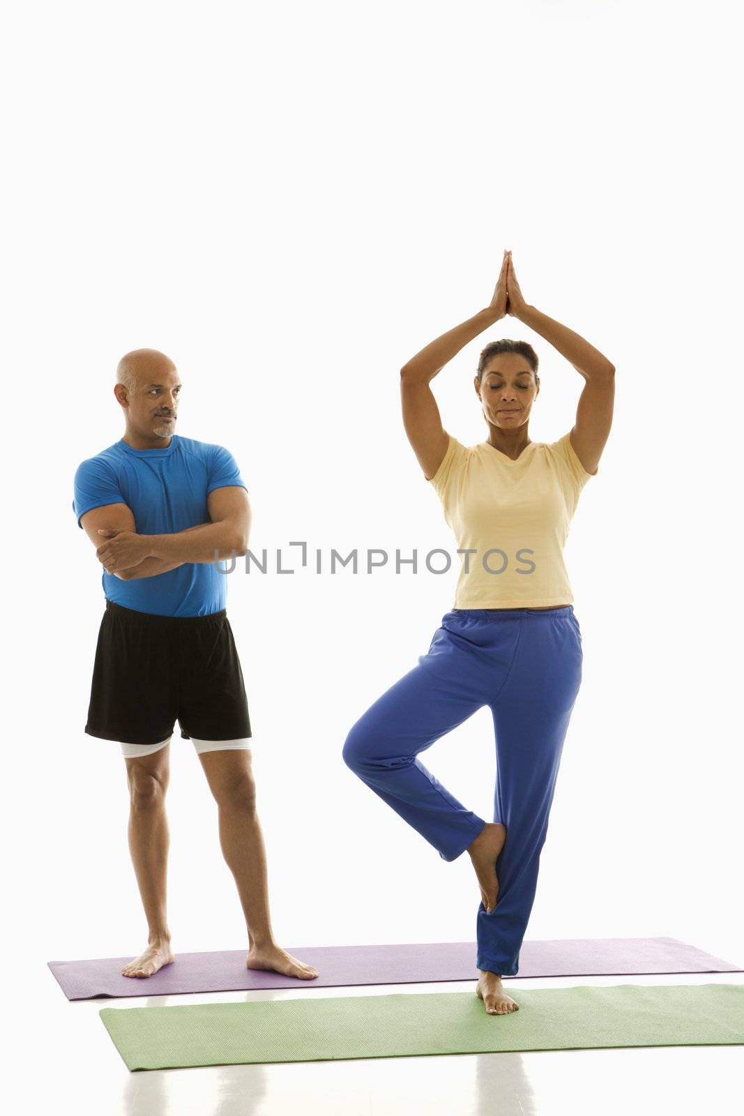 Two people practicing yoga. by iofoto