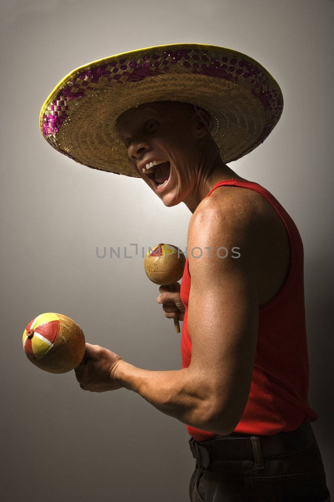 Portrait of a Mid-adult Caucasian male wearing sombrero holding maracas.