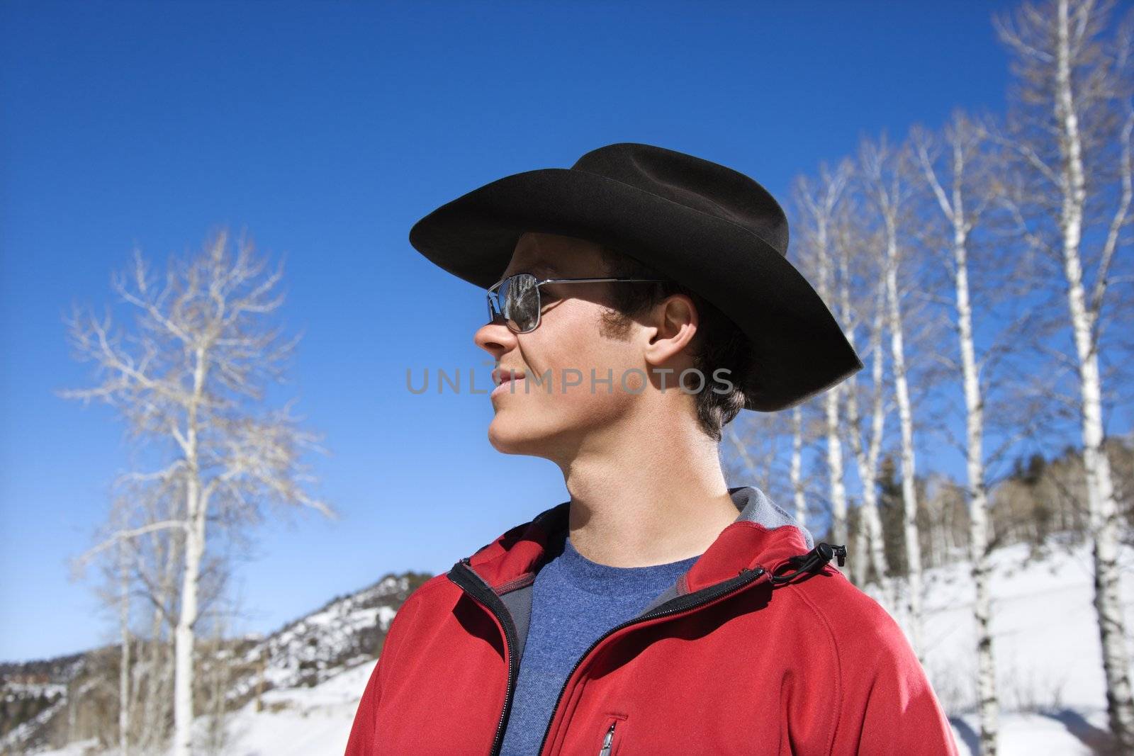 Young adult Caucasian cowboy wearing sunglasses and cowboy hat in winter.