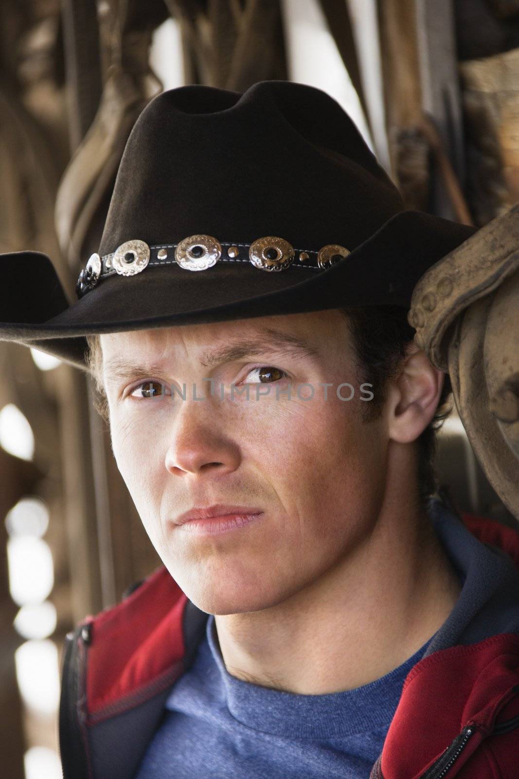 Young adult Caucasian male wearing cowboy hat looking at viewer.