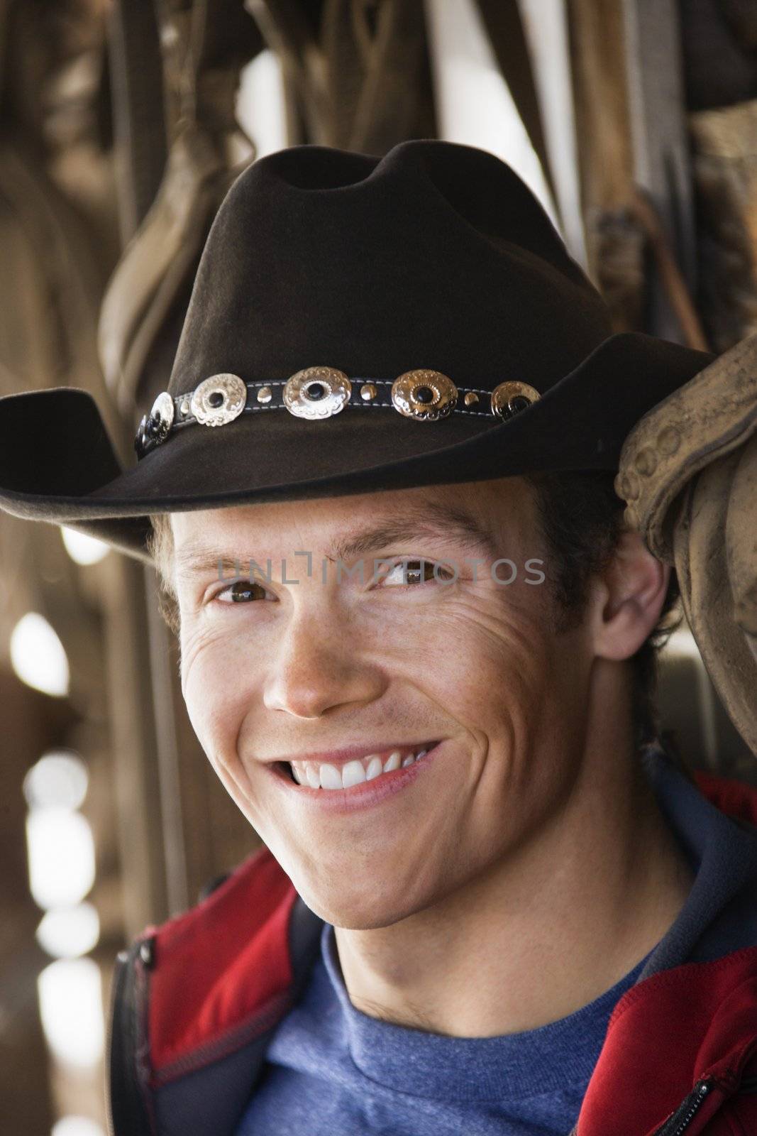 Young adult Caucasian male wearing cowboy hat smiling at viewer.