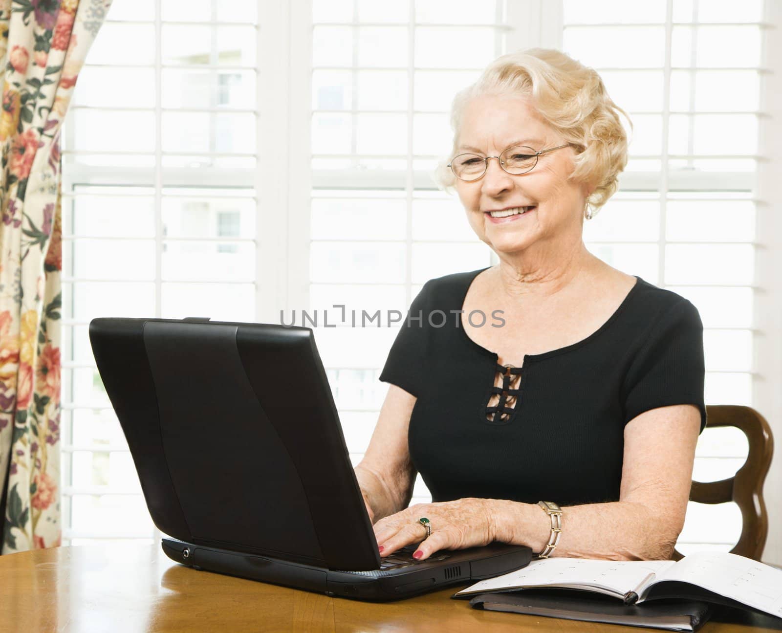 Mature Caucasian woman using laptop in living room.