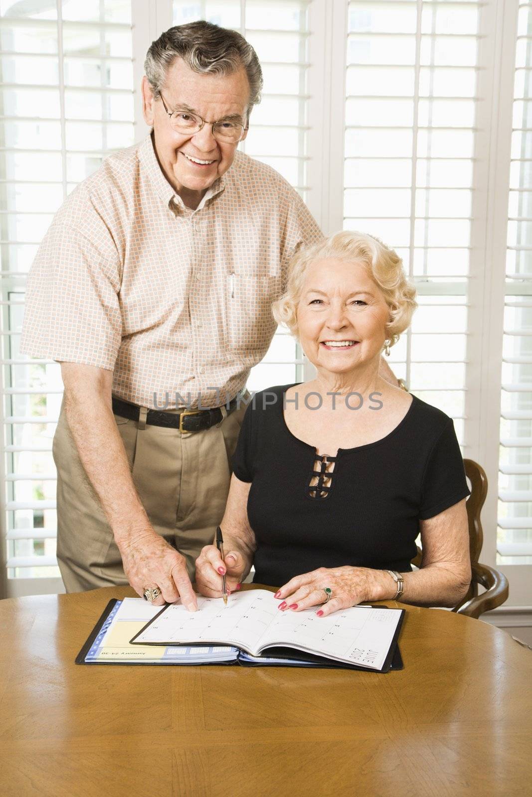 Mature Caucasian couple looking at their calendar.