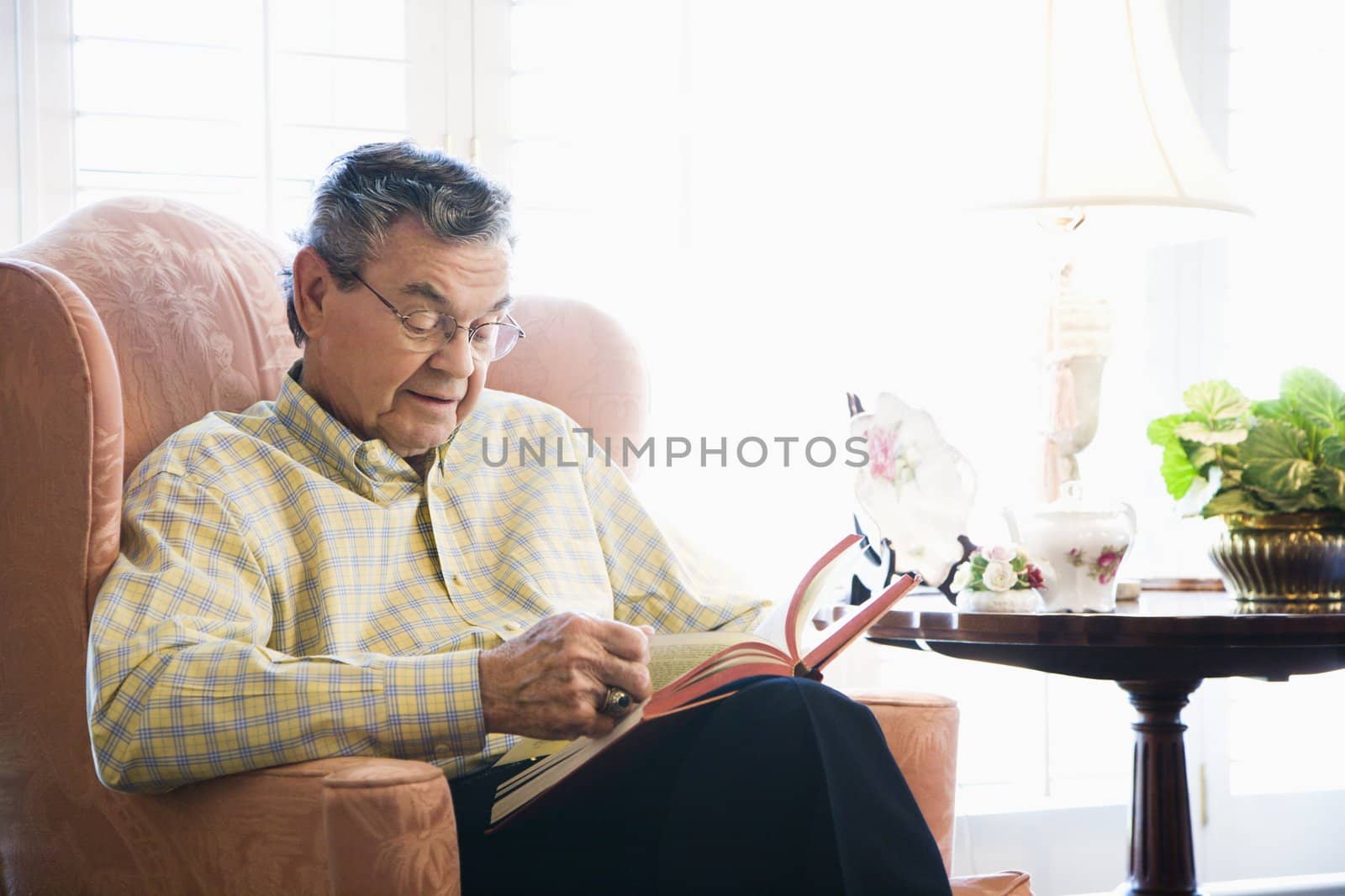 Mature Caucasian man sitting in chair reading a book.