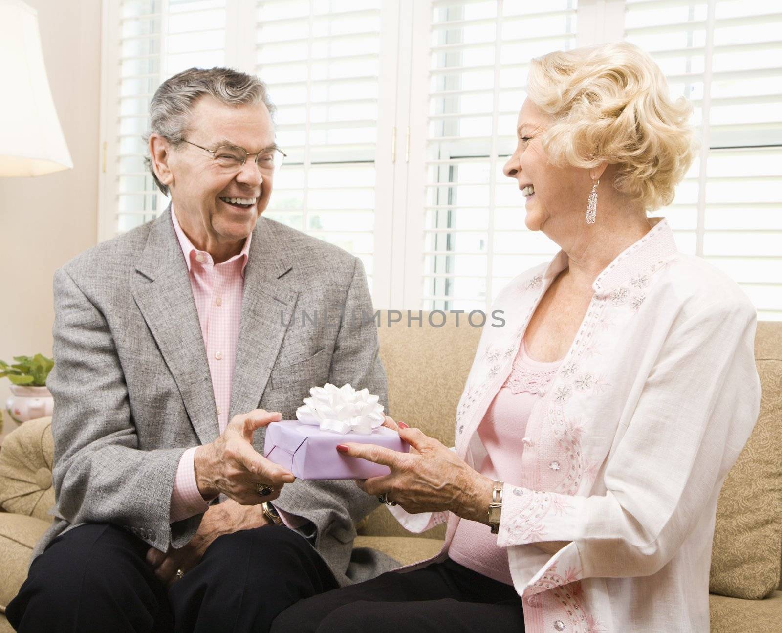 Mature Caucasian couple exchanging present.