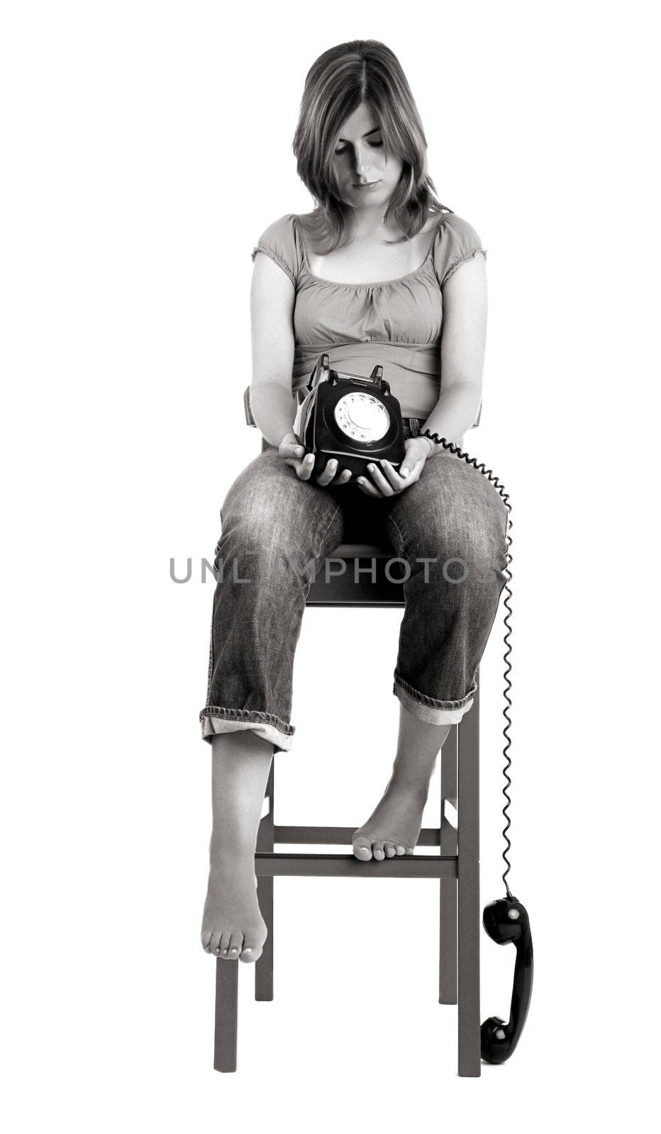 Sad woman seated in a chair with a the phone on is hands