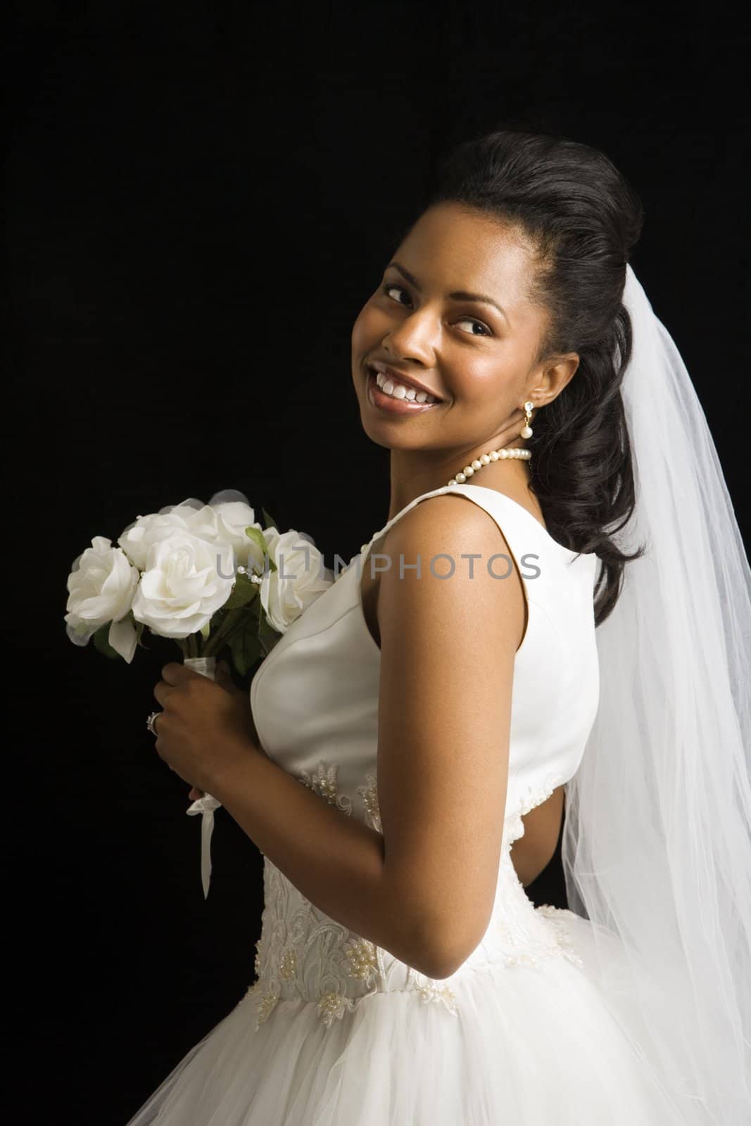 Portrait of a mid-adult African-American bride on black background.