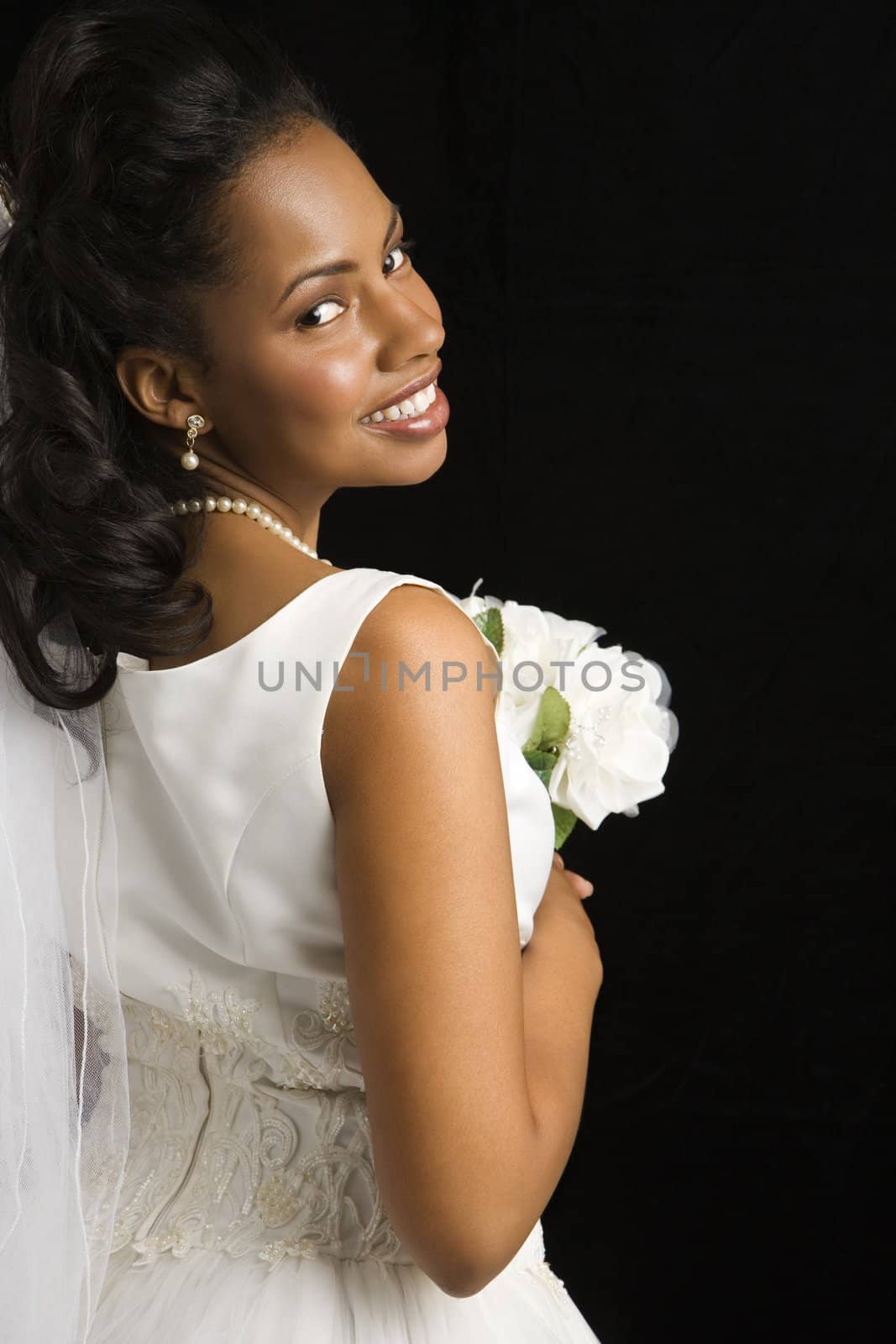 Portrait of a mid-adult African-American bride on black background.