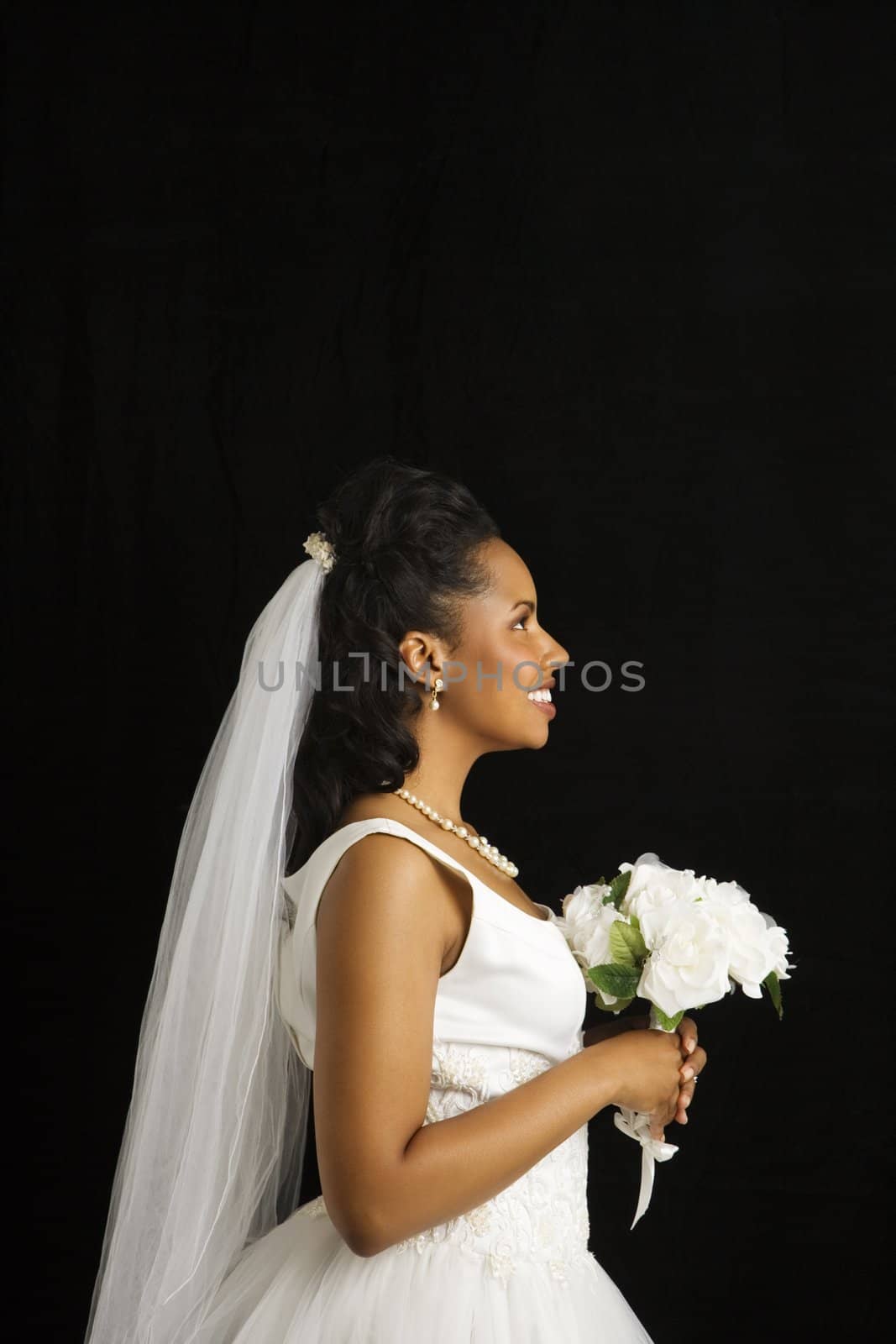 Portrait of a mid-adult African-American bride on black background.