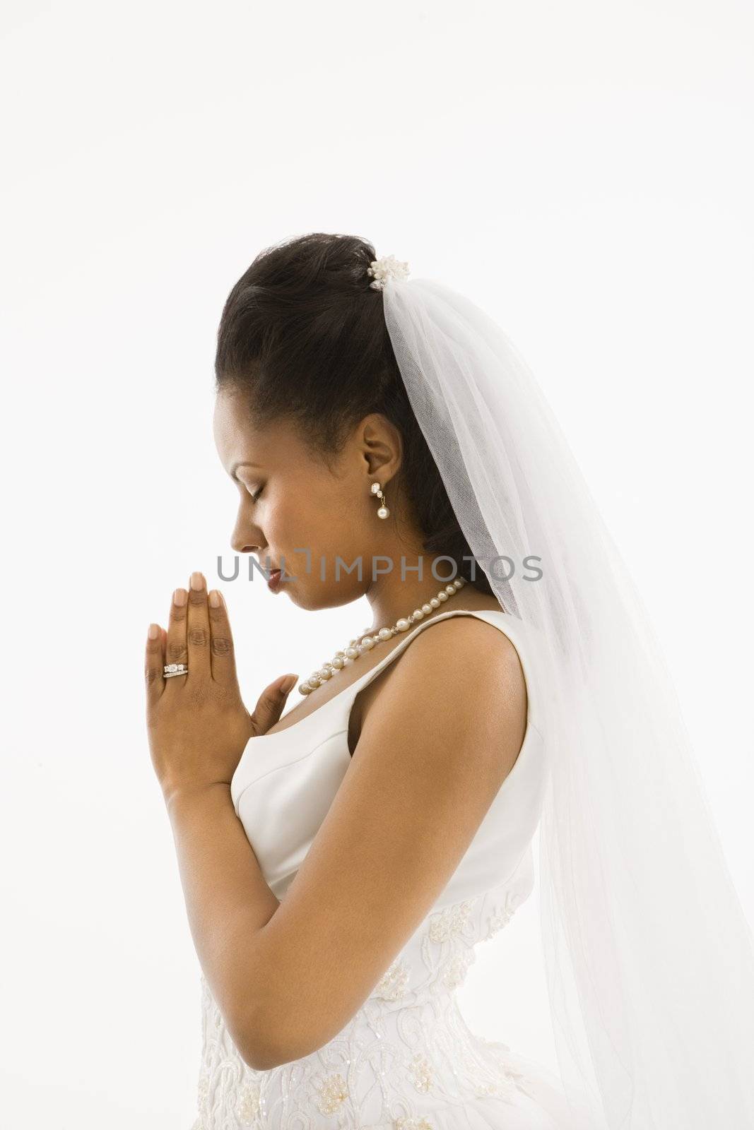 Mid-adult African-American bride praying with white background.