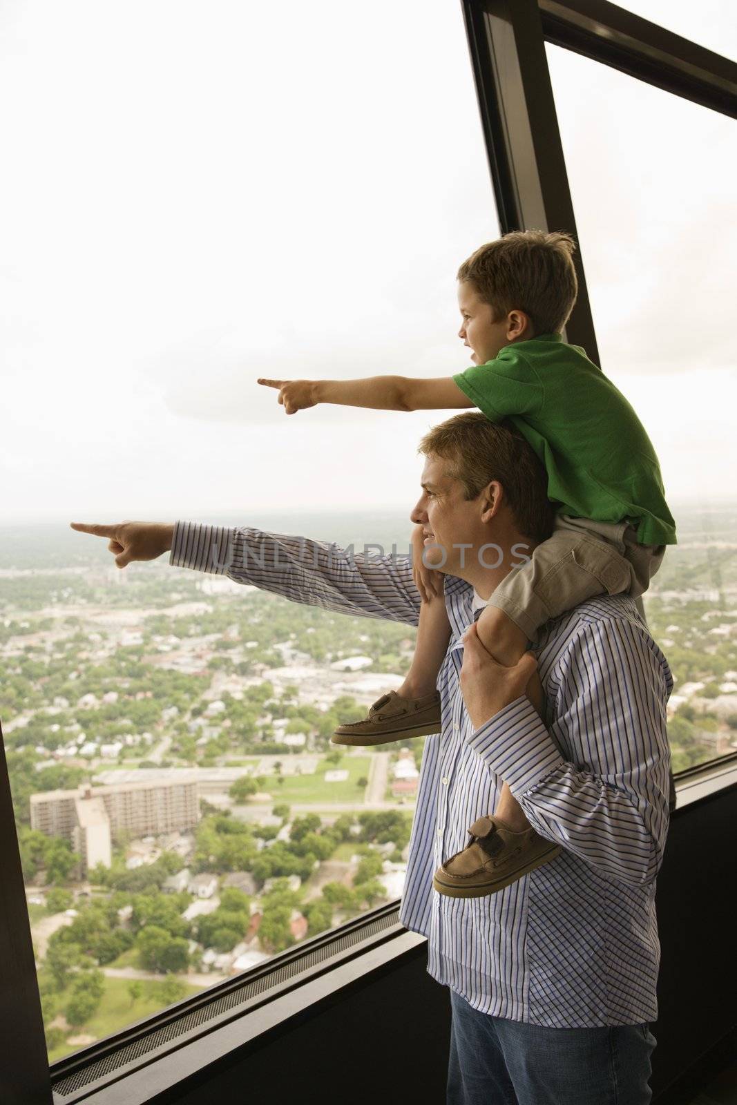 Father and son pointing from observation deck at Tower of the Americas in San Antonio, Texas.