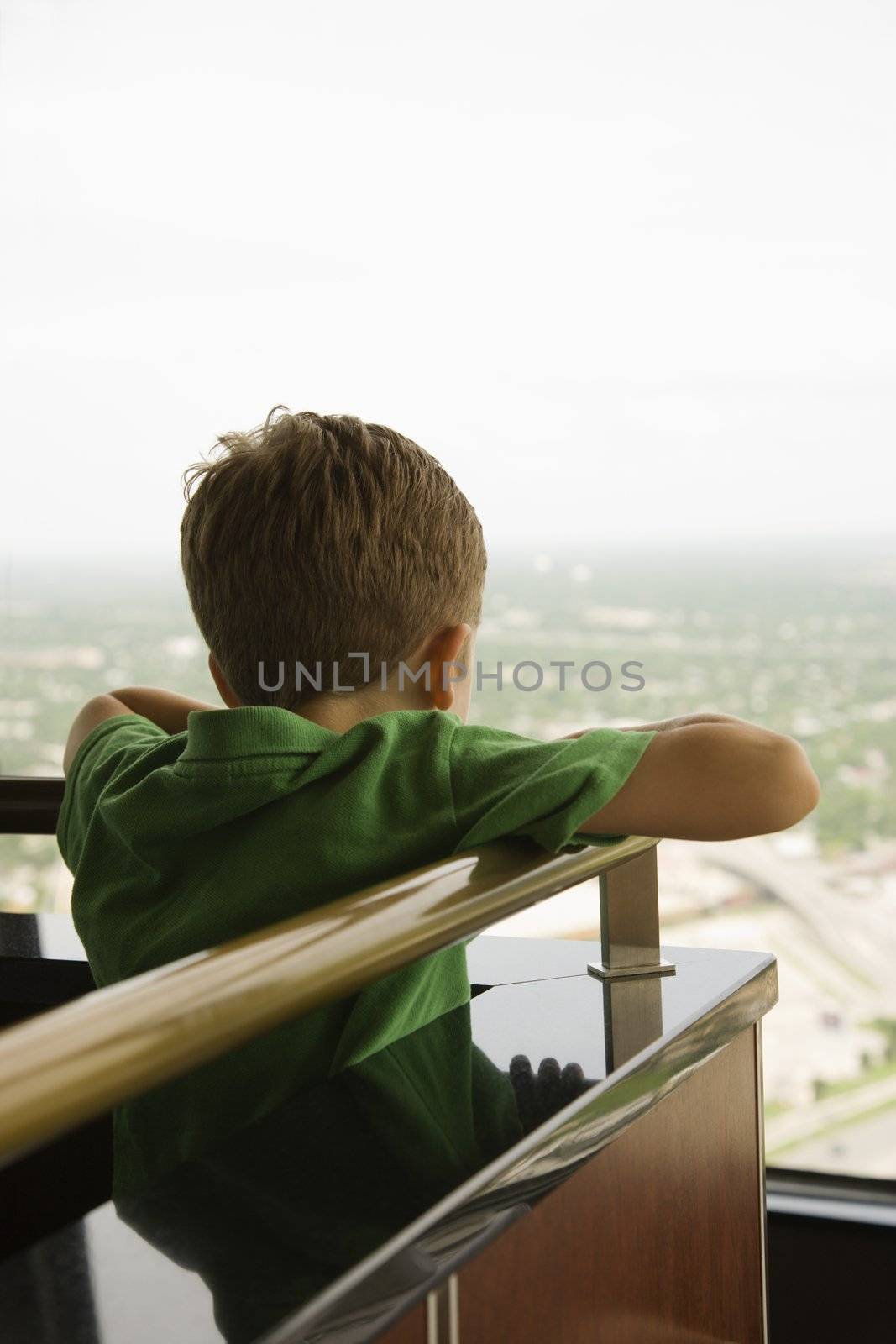 Young Caucasian boy leaning on railing at observation deck at Tower of the Americas in San Antonio, Texas.