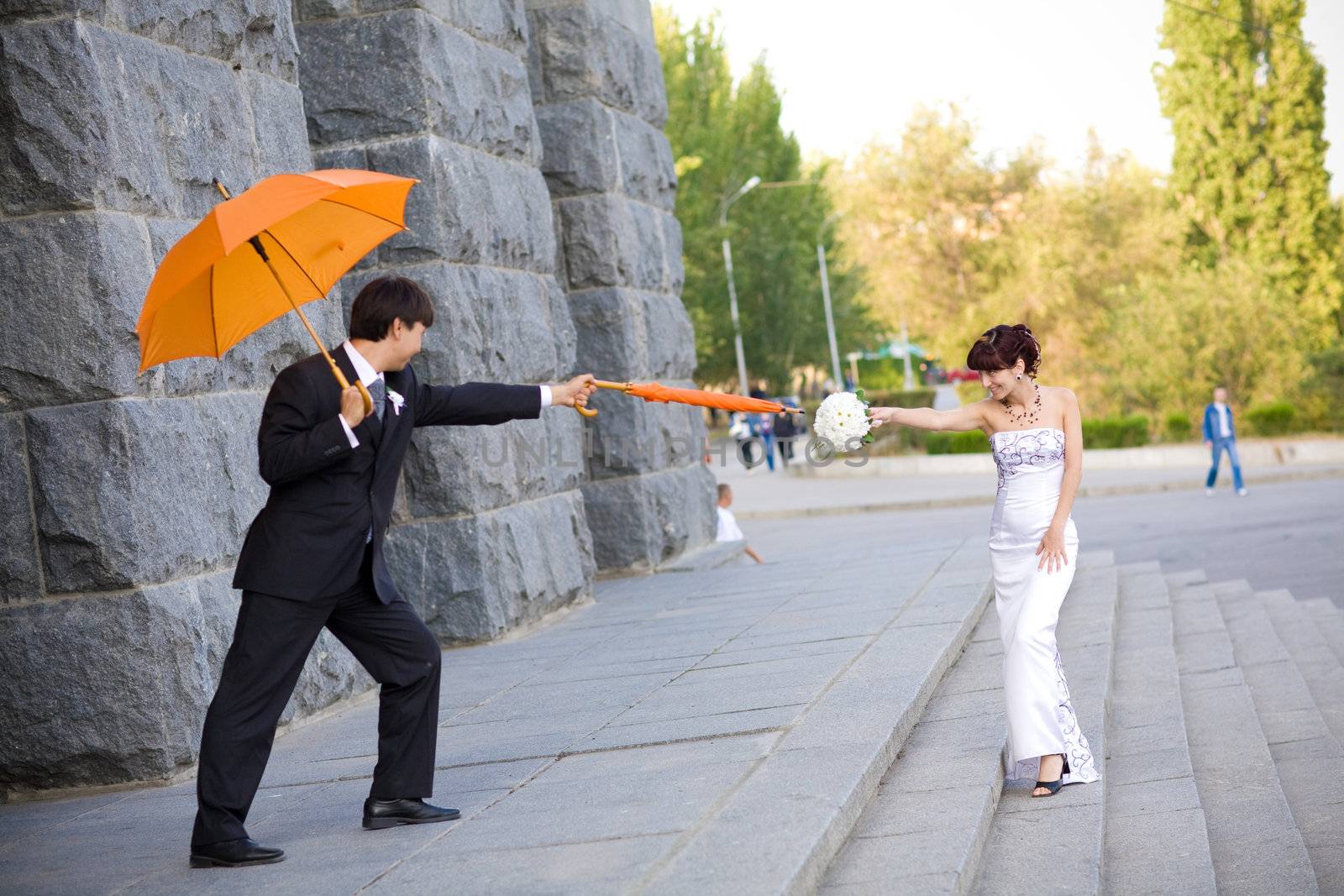 playing bride and groom with orange umbrellas 