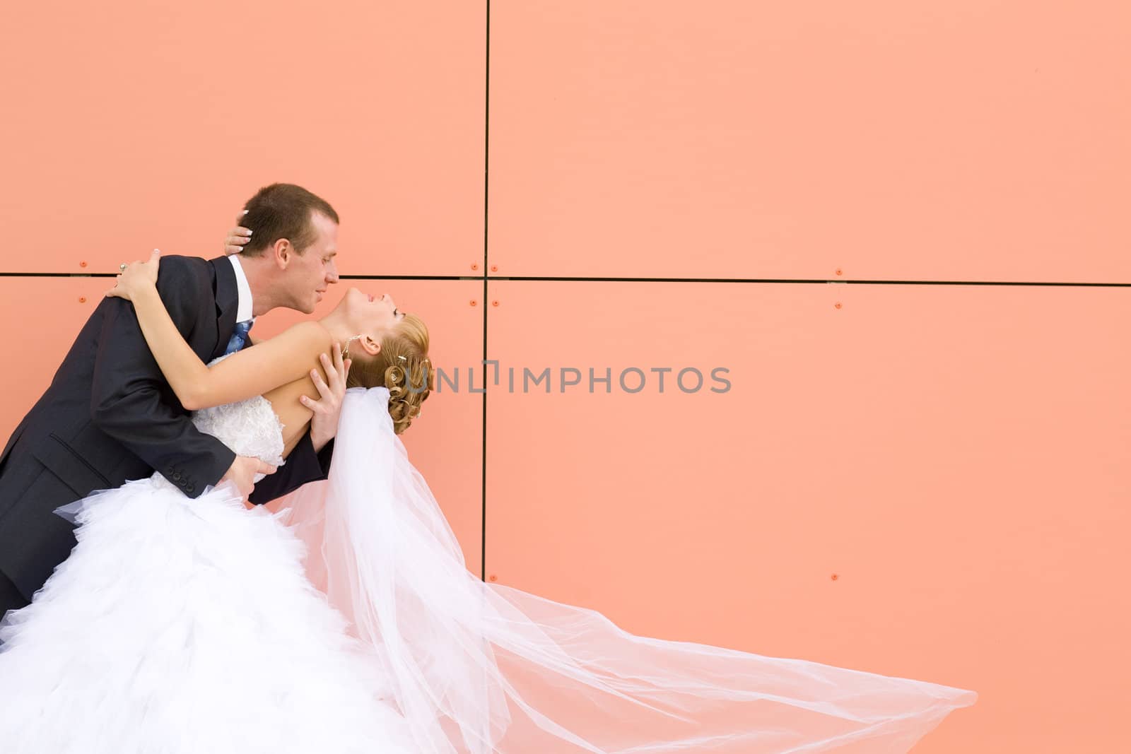 kiss of bride and groom near the wall 