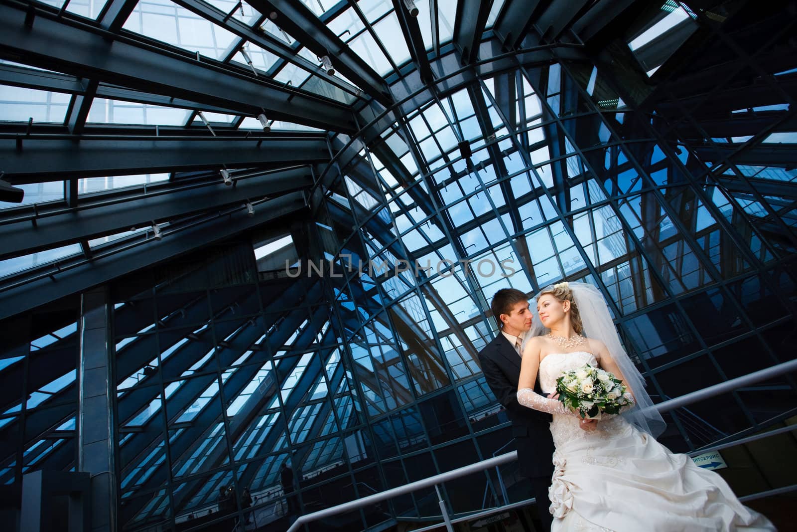 bride and groom under the glass ceiling 
