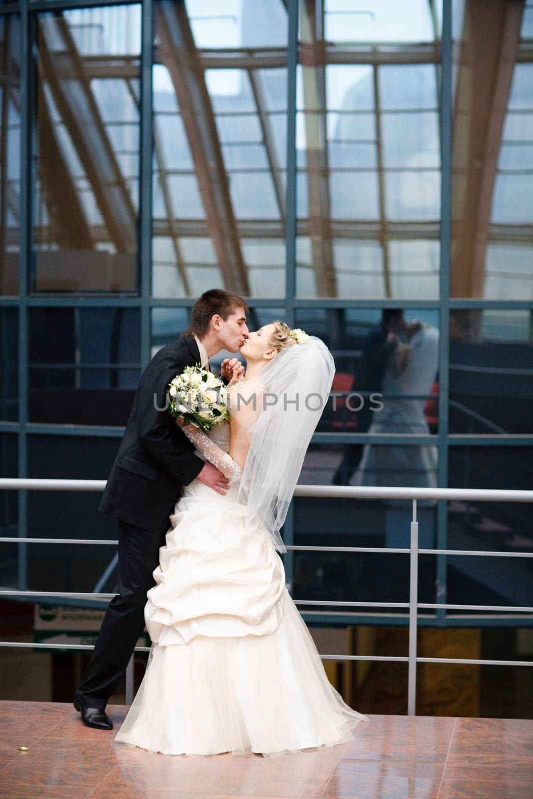 kissing bride and groom under the glass ceiling 