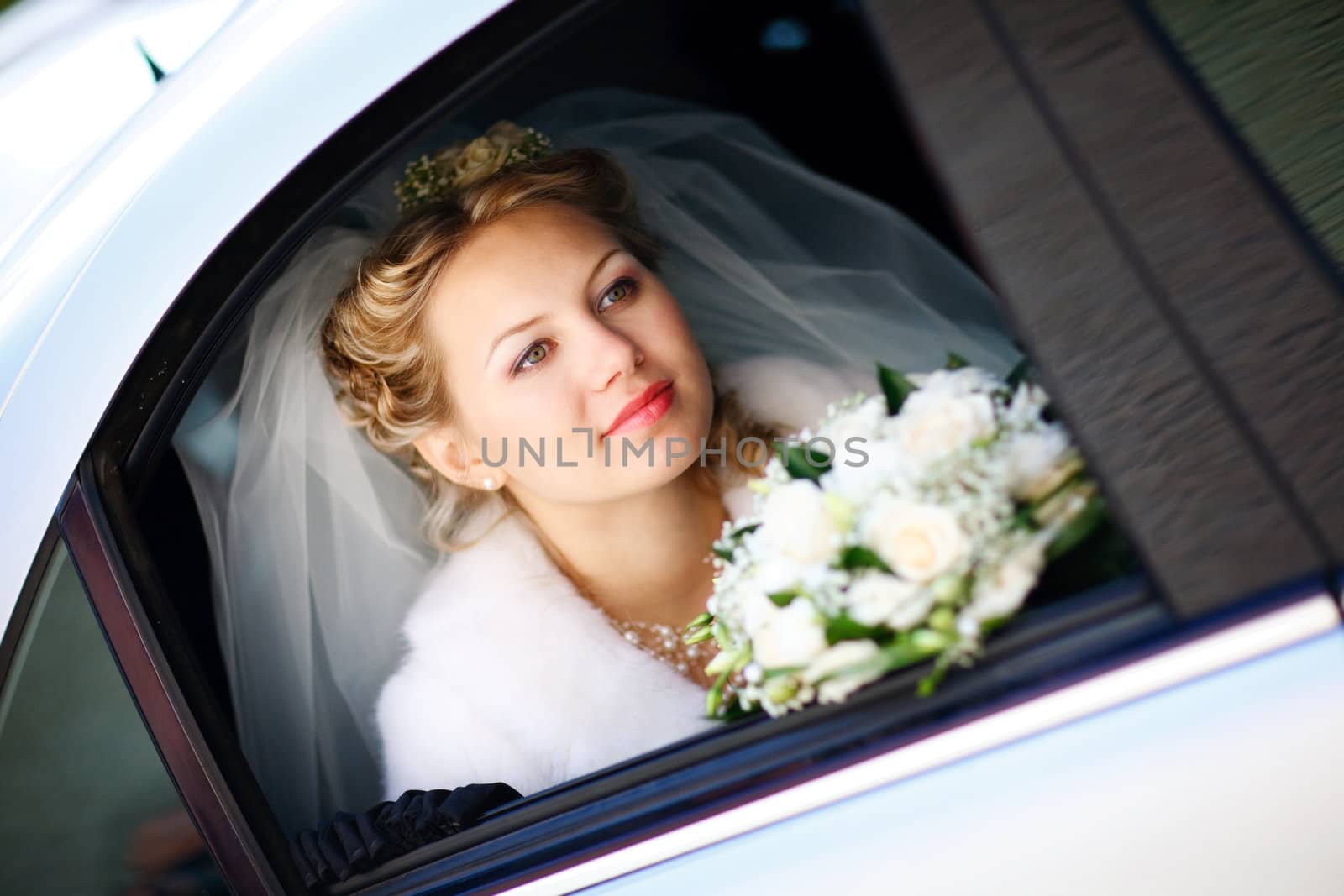 happy bride with flower bouquet siting in the car