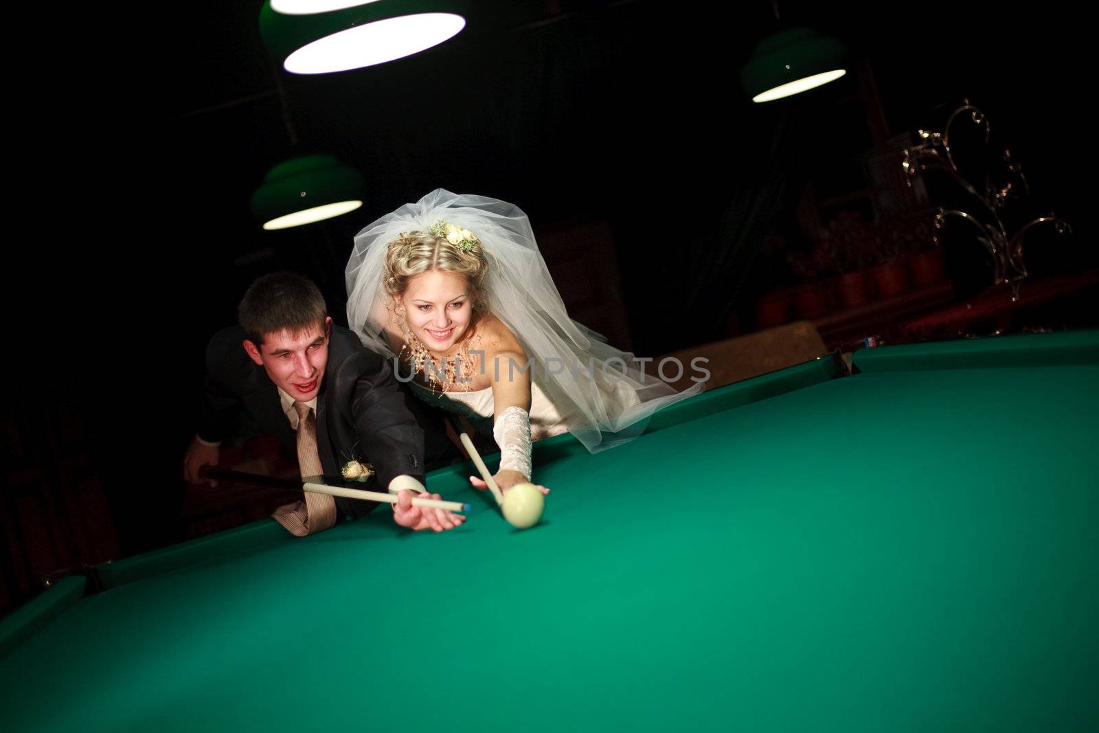 bride and groom play billiard