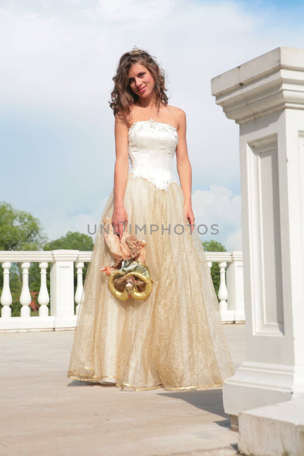 smiling girl in white-golden gown and with doll in hand