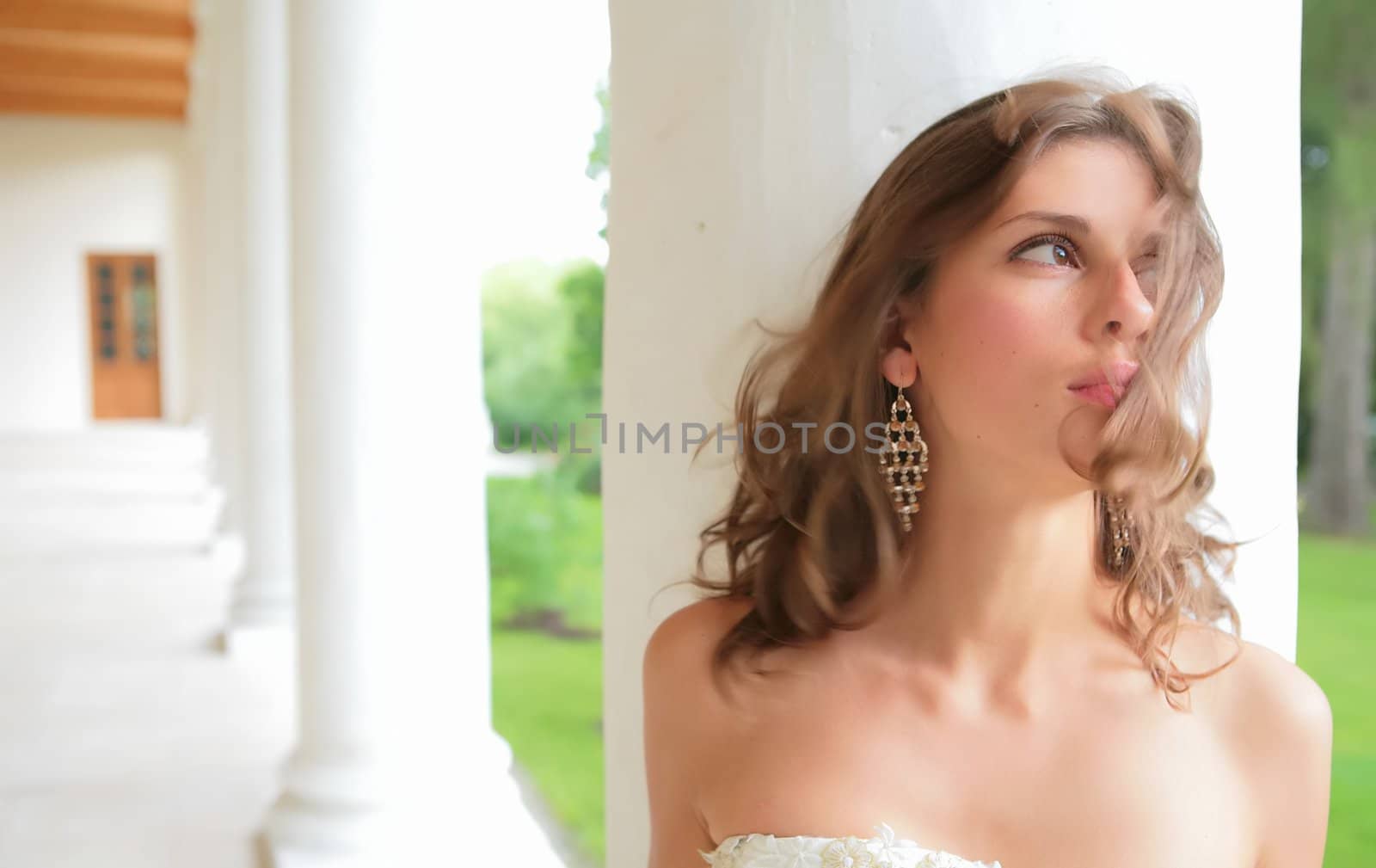 portrait of the beautiful girl on background of the white pillar of the old-time building